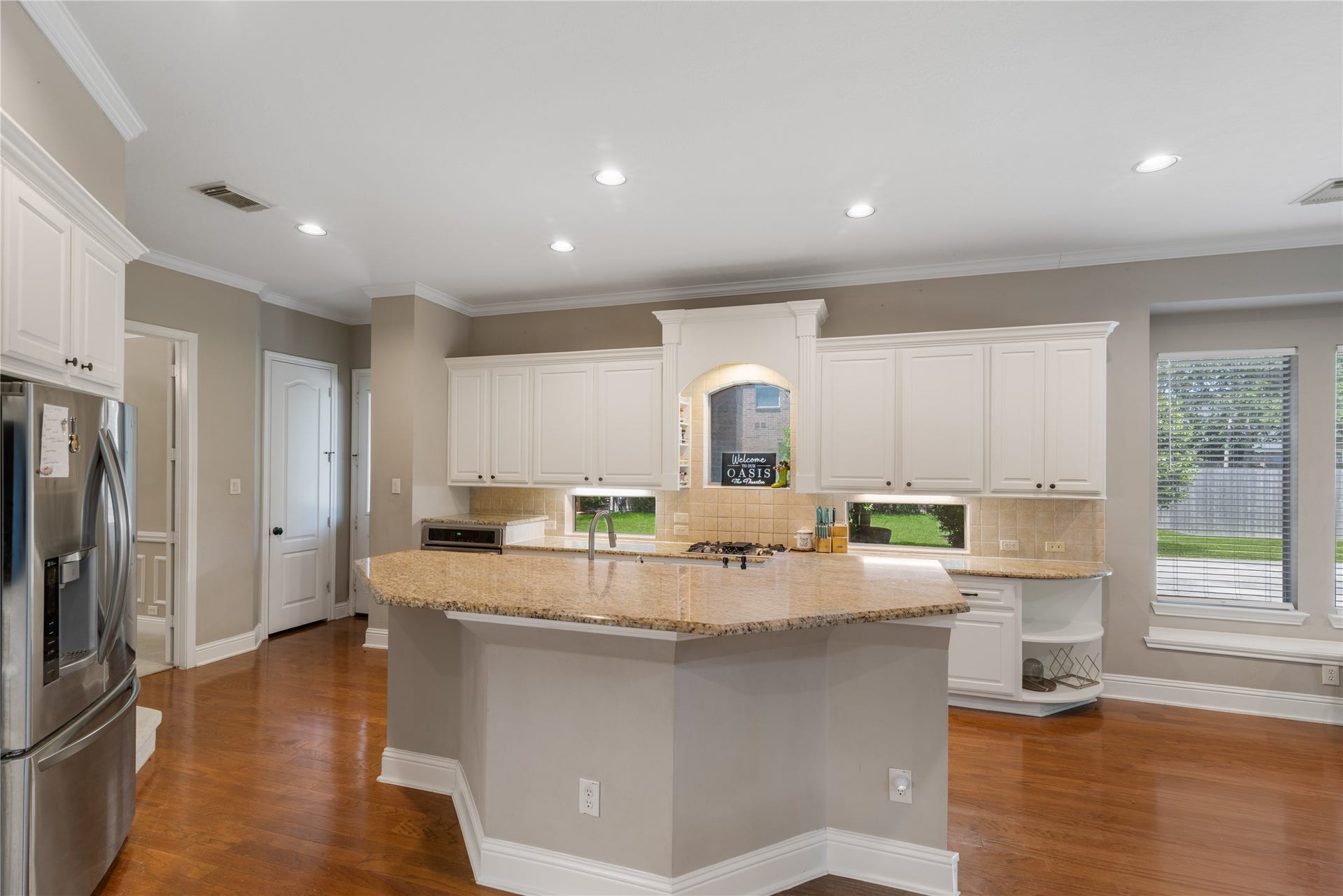 2525 W Ranch Drive, Friendswood, TX 77546 The large island offers excellent workspace and seating, while recessed lighting and big windows fill the space with natural light.
