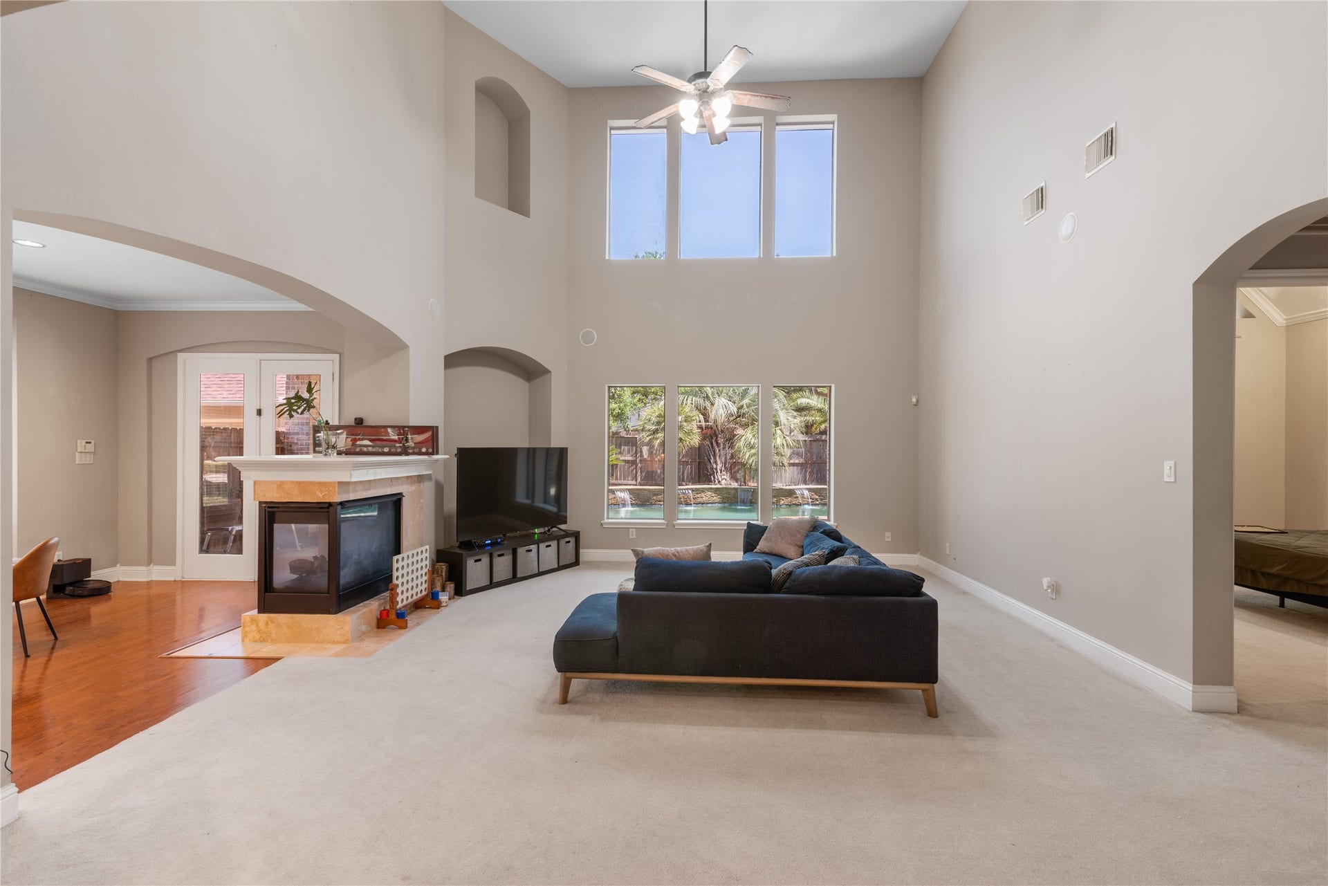 2525 W Ranch Drive, Friendswood, TX 77546 Light-filled family room with high ceilings, double-sided fireplace, and views of the pool area.