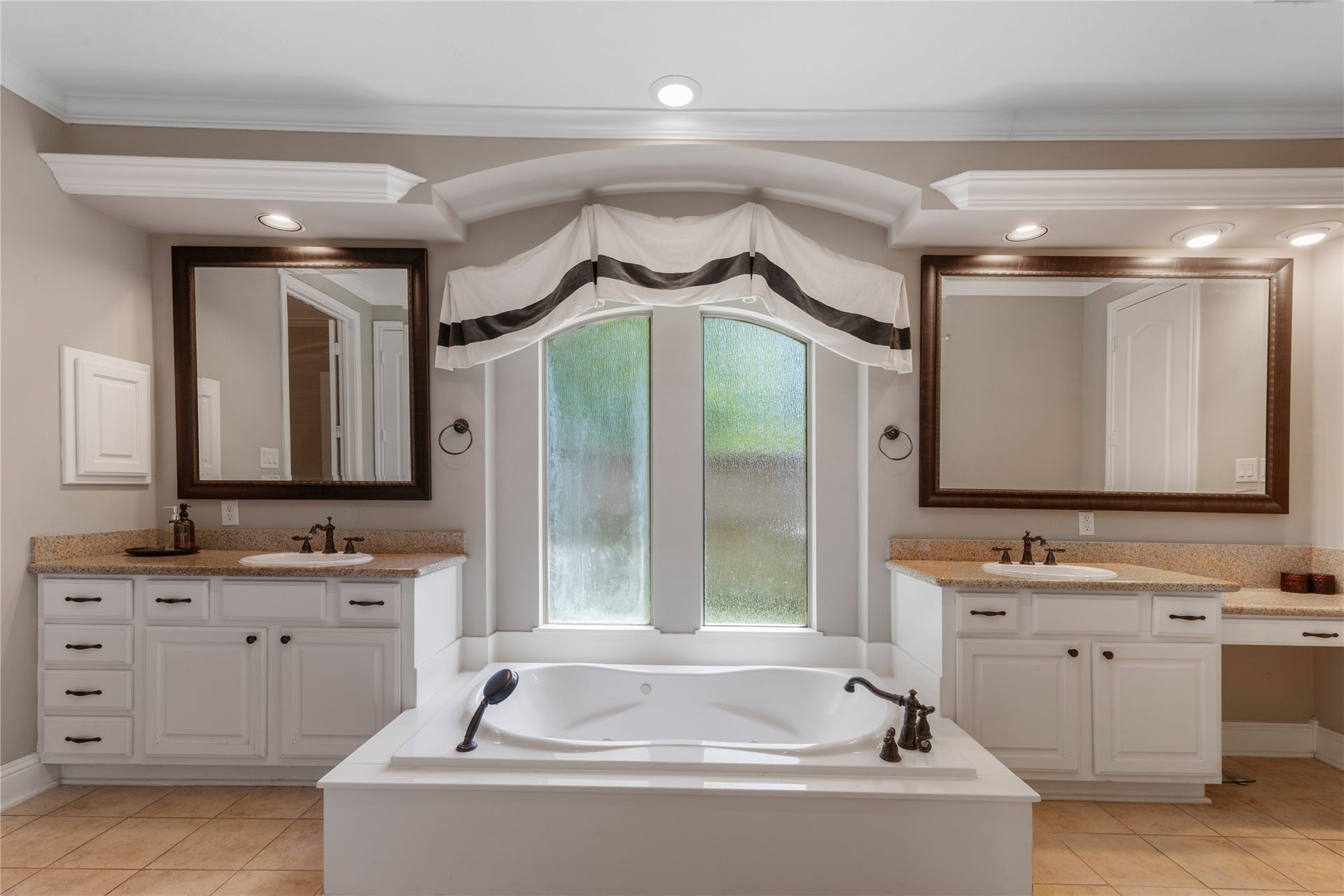 2525 W Ranch Drive, Friendswood, TX 77546 Elegant master bath featuring dual vanities with granite countertops and a large soaking tub for a spa-like retreat within the suite.