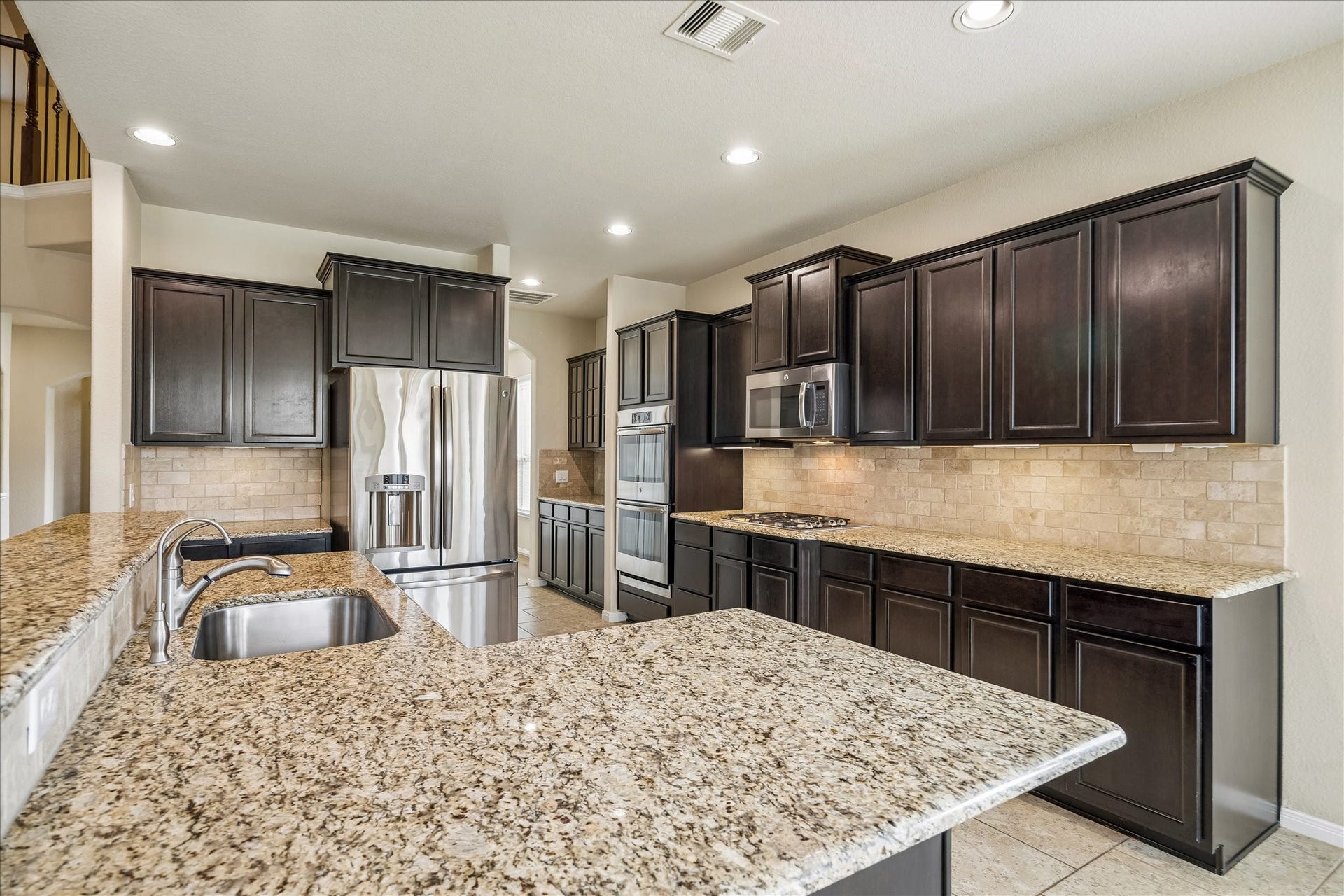 30 Glade Park Drive, Missouri City, TX 77459 Whether you're cooking for a crowd or preparing a quick weeknight dinner, this spacious kitchen has room to make it happen. Granite countertops, tile backsplash with under-cabinet lights, rich wood cabinetry, stainless steel appliances, and a large island with bar seating bring the joy back into cooking.