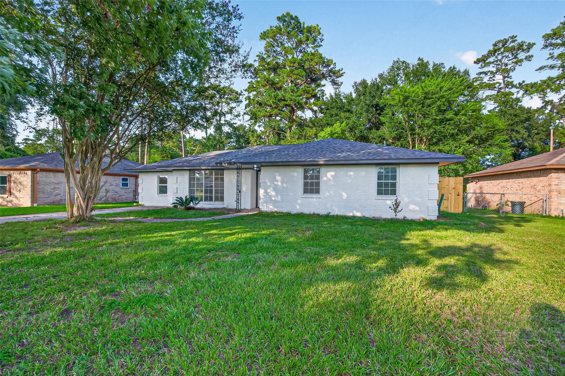 Large front yard with mature oak tree providing ample shade and excellent curb appeal.