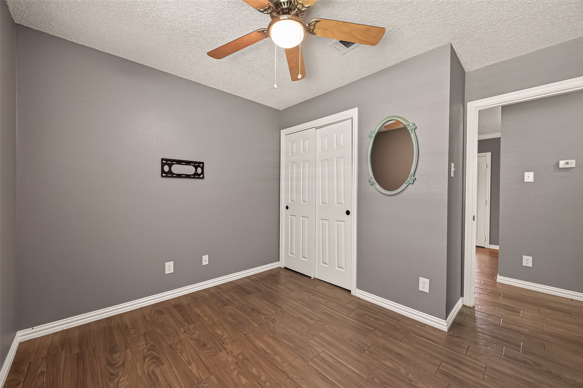 7502 Nightingale Circle, Texas City, TX 77591 Inviting secondary bedroom featuring durable wood-look tile flooring, neutral paint, a ceiling fan with light, and a spacious closet with sliding doors. A versatile space ideal for a bedroom, home office, or guest room.