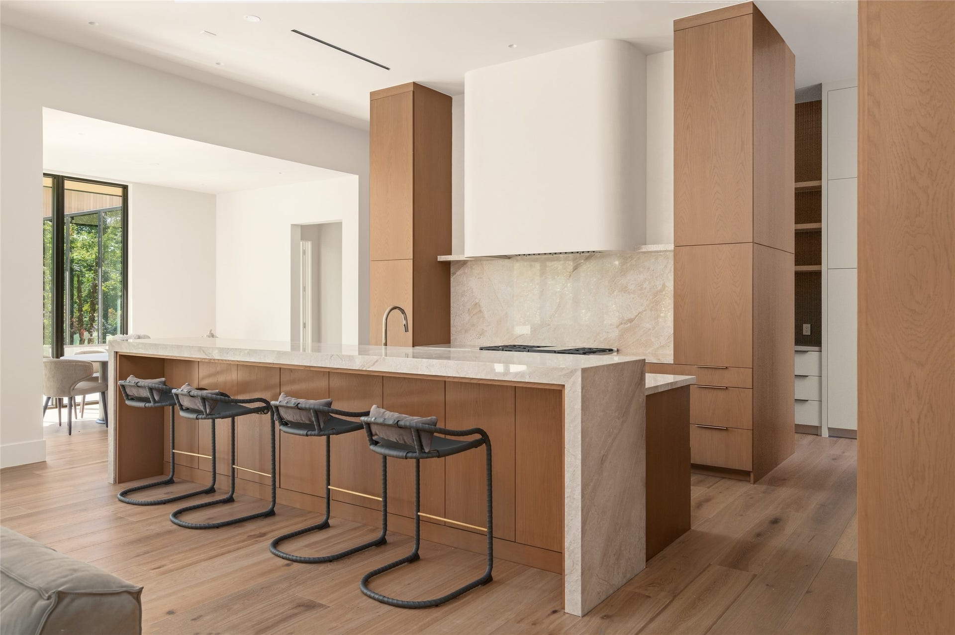 11 Tiel Way, Houston, TX 77019 The centerpiece of the chef's kitchen is a striking 13-foot waterfall island finished in Daino Reale marble, offering generous seating and preparation space while complementing the warmth of the custom white oak cabinetry.