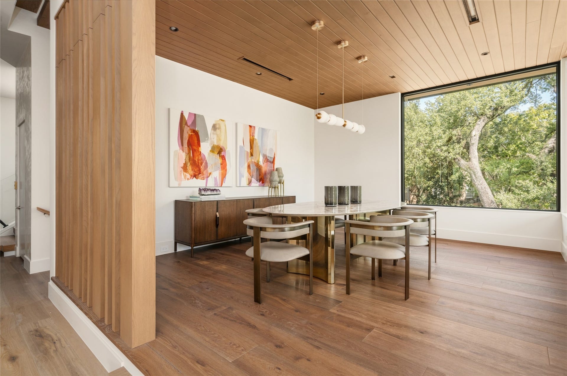 11 Tiel Way, Houston, TX 77019 The formal dining room is beautifully defined by a stained tongue-and-groove ceiling, custom wood-slat partitions, and wide-plank European oak flooring, while an oversized picture window frames the treetops like a living work of art.