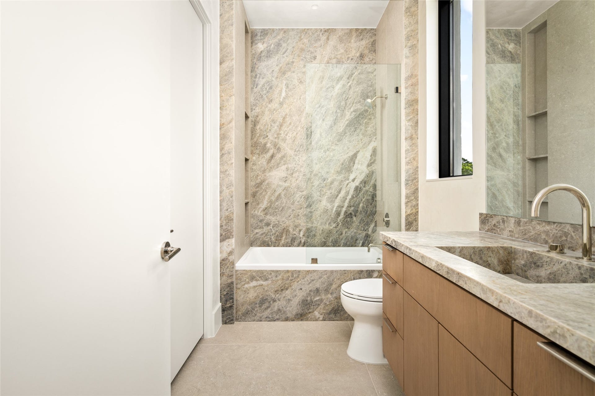11 Tiel Way, Houston, TX 77019 The ensuite bathroom showcases a Cielo quartzite vanity with an integrated sink and elegant Luxe Stone Chablis flooring, and a custom backlit mirror. Sophisticated finishes and clean lines create a sleek, contemporary space.