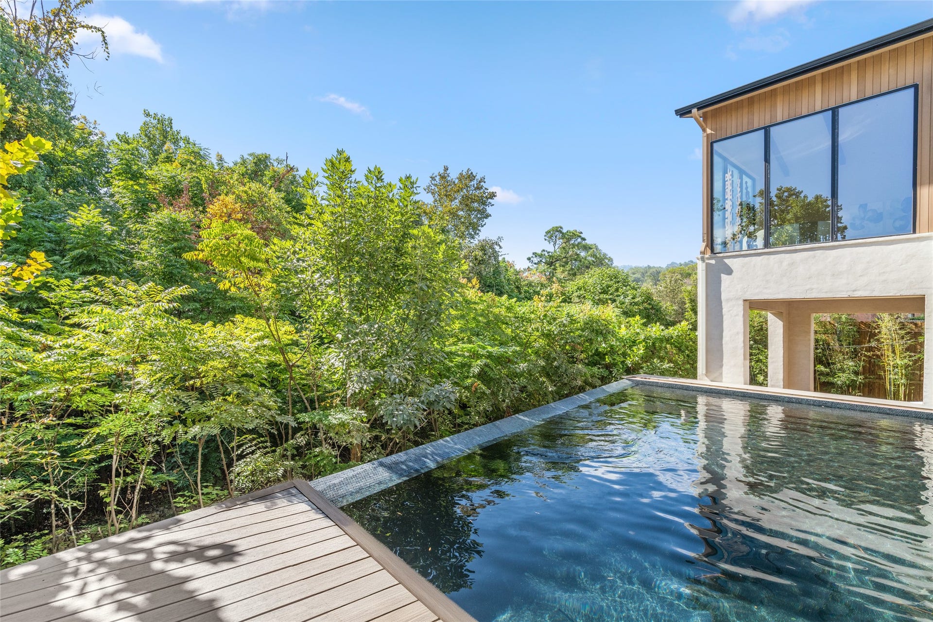 11 Tiel Way, Houston, TX 77019 Suspended above the wooded landscape, the vanishing-edge pool creates a stunning visual connection with the surrounding greenery, offering a peaceful setting that feels worlds away from the heart of River Oaks.