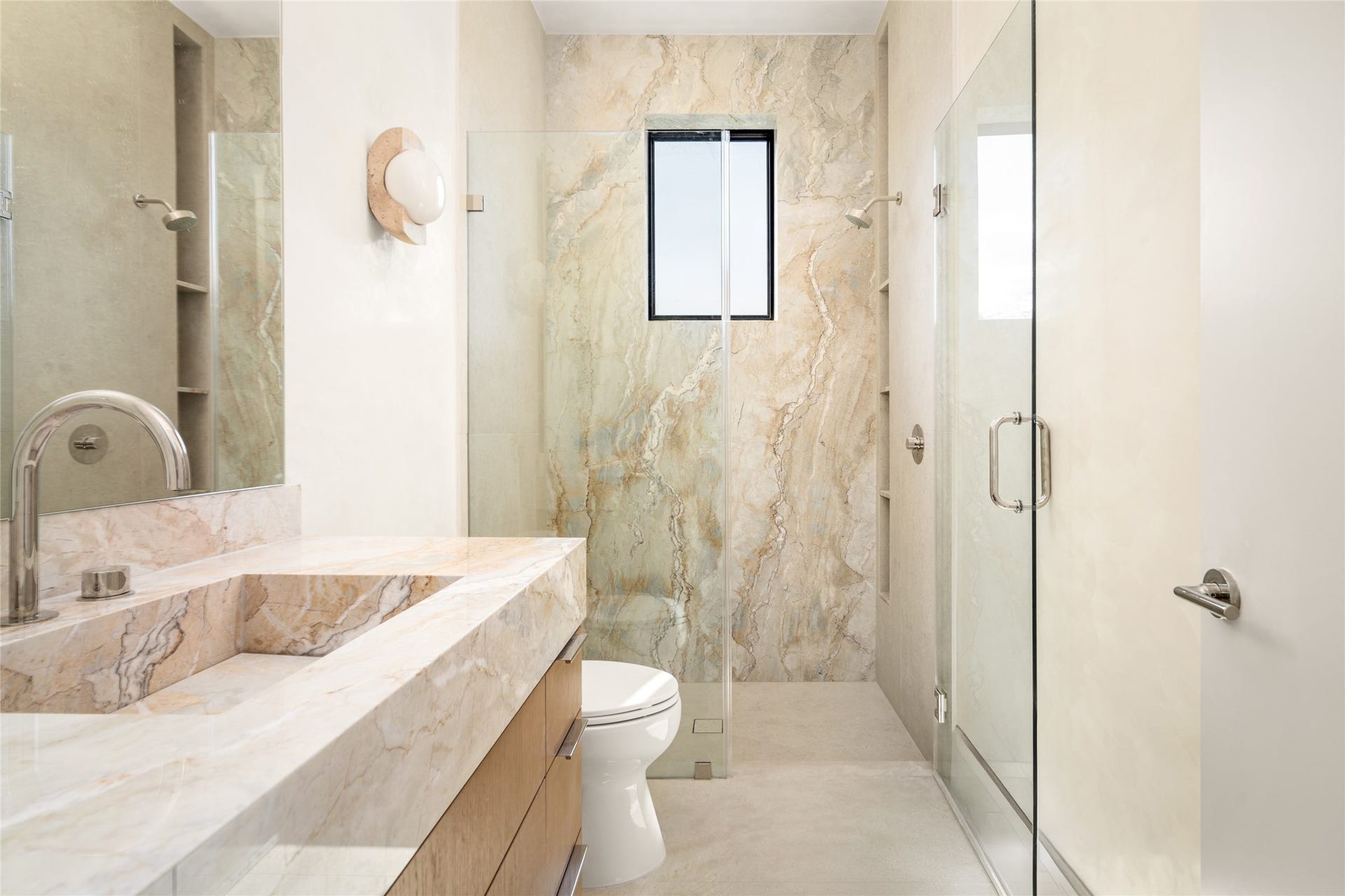 11 Tiel Way, Houston, TX 77019 A sleek floating vanity topped with Dolce Vita quartzite and an integrated sink adds a luxurious touch to this ensuite bathroom, while Luxe Stone Montpellier wall and floor tile beautifully complements the spacious glass-enclosed shower.