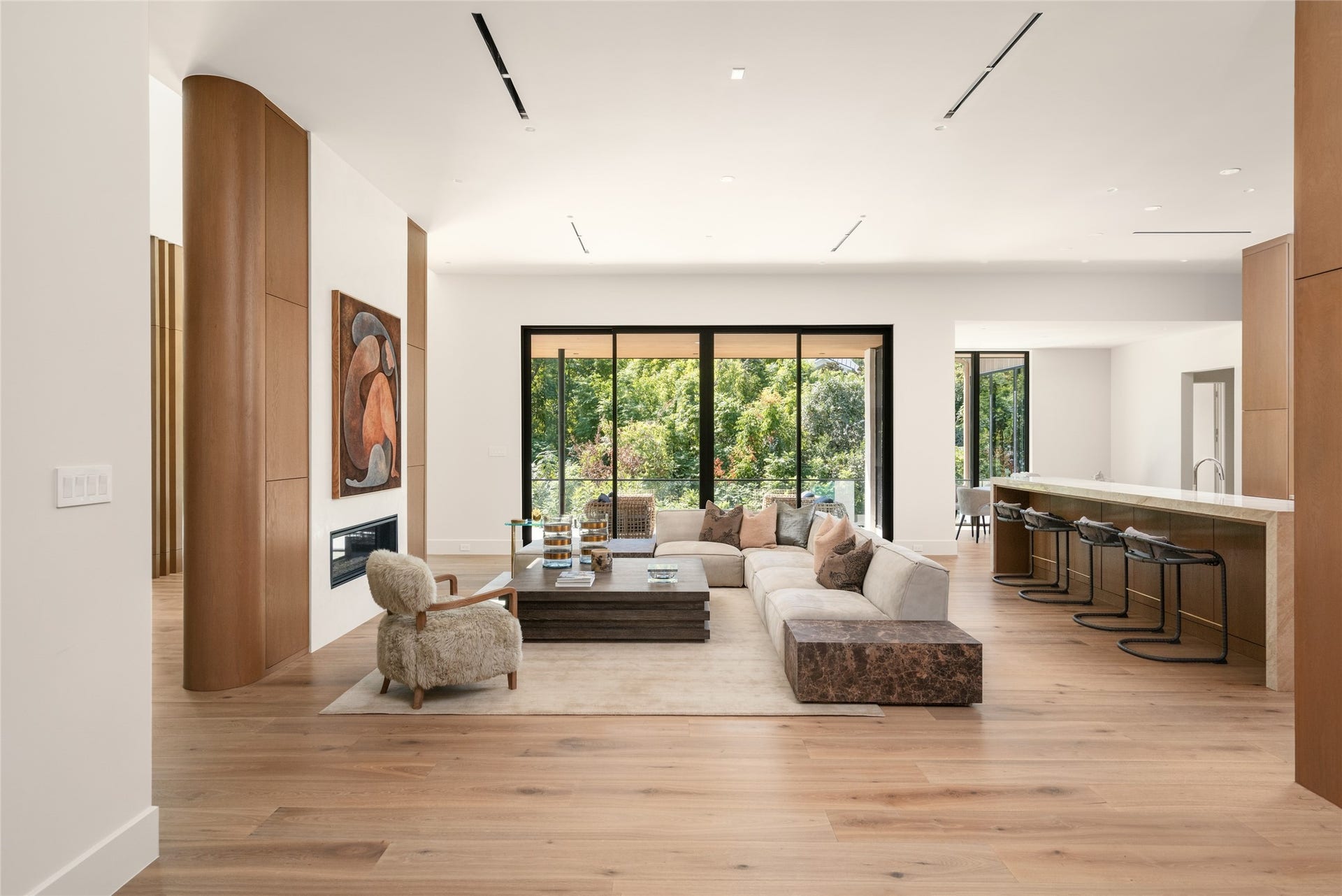 11 Tiel Way, Houston, TX 77019 A beautifully composed living space where the family room and kitchen come together, with warm wood finishes, thoughtfully curated architectural details, and expansive glass creating an inviting setting for both relaxing and entertaining.