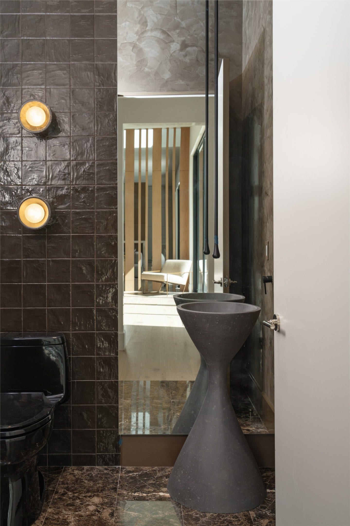 11 Tiel Way, Houston, TX 77019 A moody, sophisticated powder room near the entertaining bar makes a bold statement with Emperador Dark marble flooring, rich cocoa Zellige tile, textured Roman clay walls, and a sculptural stone basin with a suspended glass faucet.