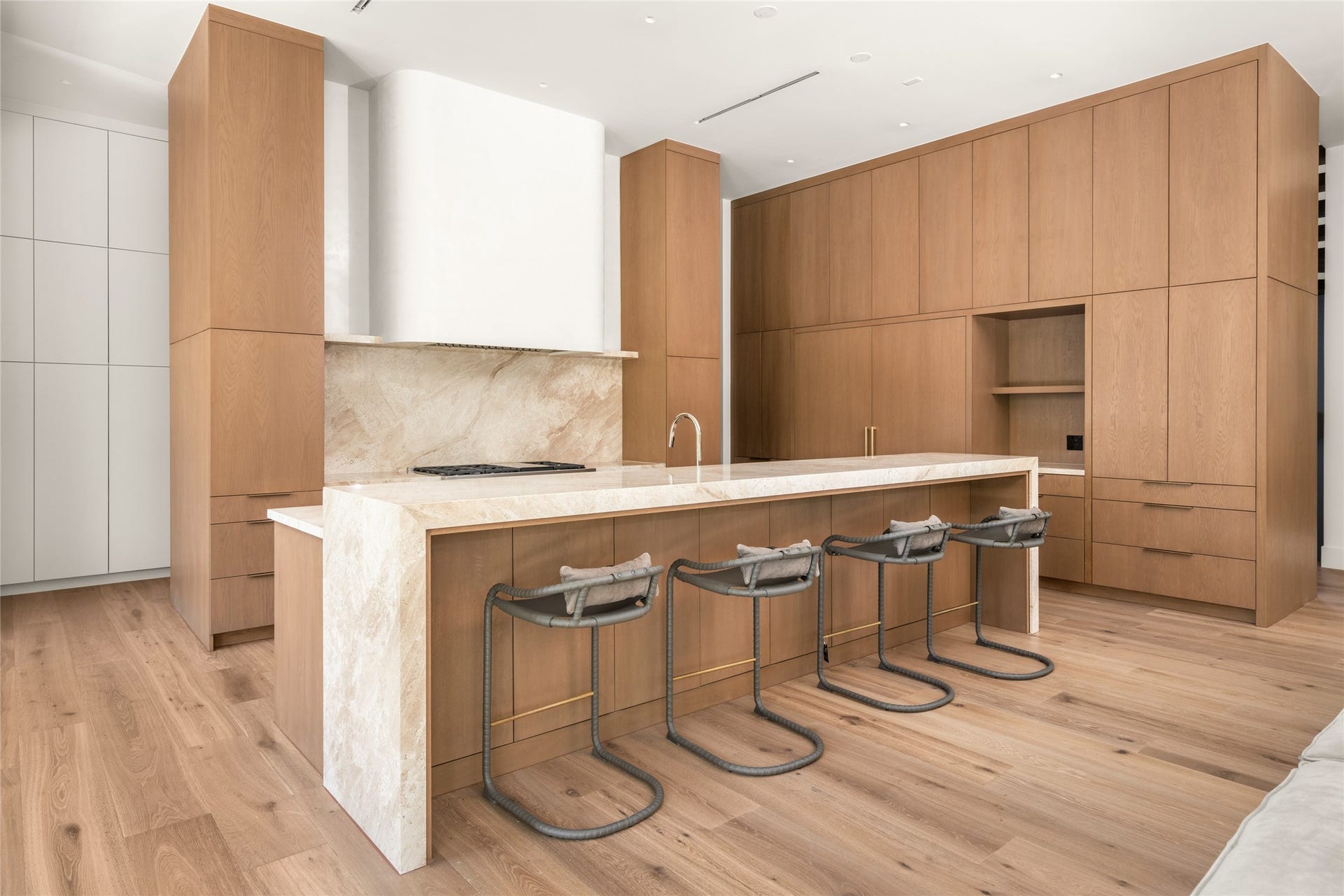 11 Tiel Way, Houston, TX 77019 Floor-to-ceiling custom white oak cabinetry provides extensive storage while seamlessly concealing a 72-inch Sub-Zero refrigerator/freezer and dual panel-ready dishwashers, preserving the kitchen's clean architectural design.