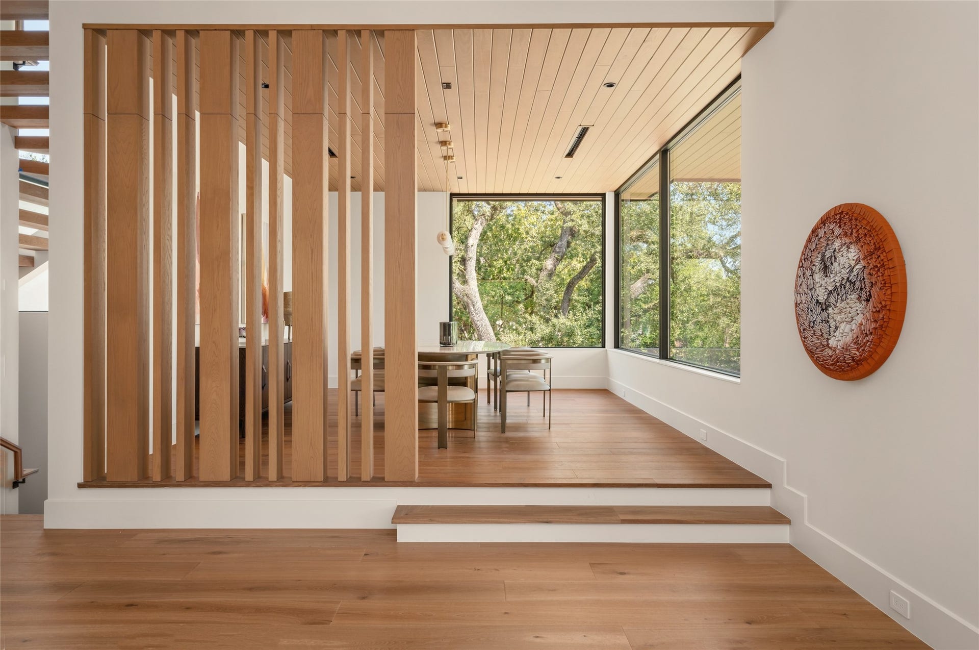 11 Tiel Way, Houston, TX 77019 A subtle change in elevation gives the dining room its own identity, while custom white oak slatted partitions define the space without closing it off. Expansive windows bring in natural light and frame the surrounding trees.