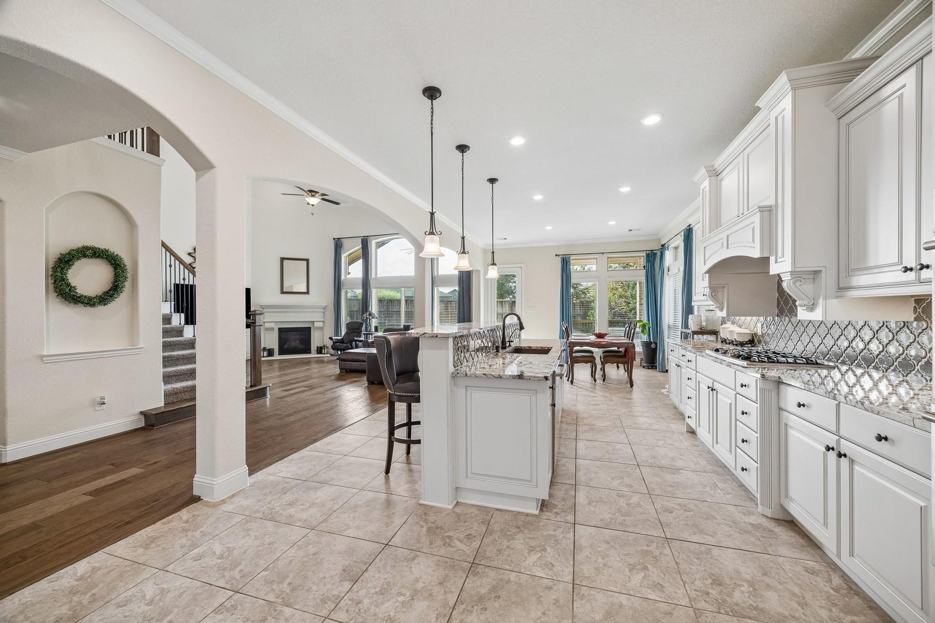 6031 Granite Shadow Lane, Porter, TX 77365 Designer pendant lighting, decorative vent hood, elegant tile backsplash.