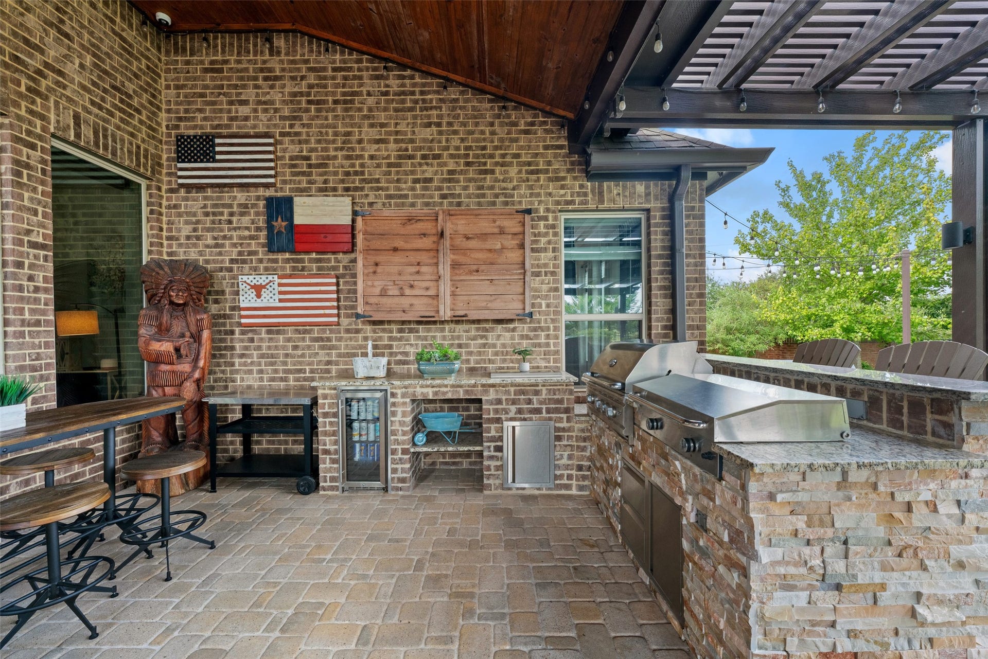 23926 Arcola Glen Lane, Katy, TX 77493 Premium outdoor kitchen featuring stone paver decking and a stone-clad built-in grill with a raised bar for seating.