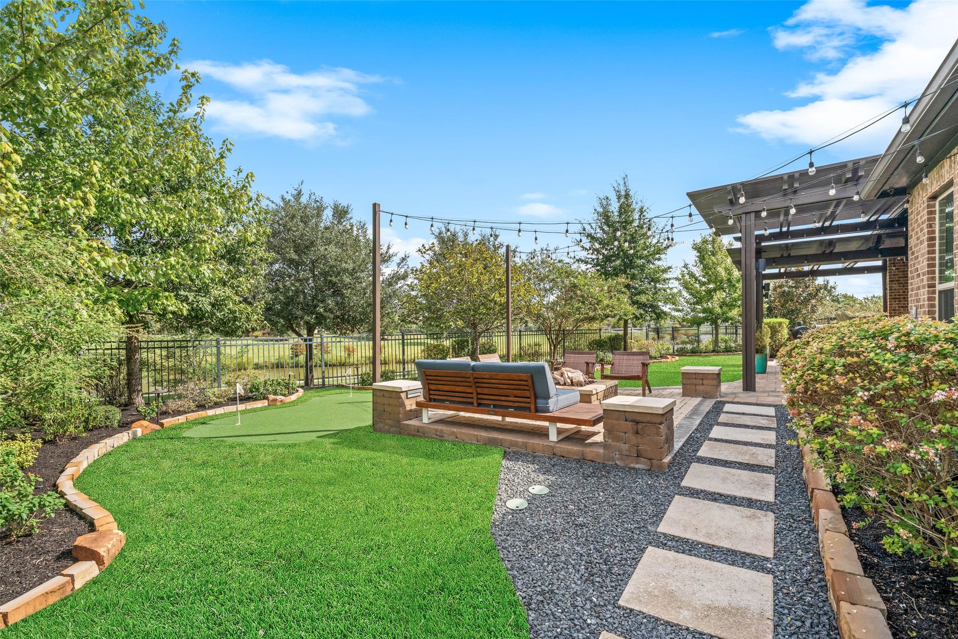 23926 Arcola Glen Lane, Katy, TX 77493 Relaxing outdoor retreat featuring a custom fire pit and spacious lounge area, perfectly complemented by a low maintenance turf backyard and lush landscaped beds.
