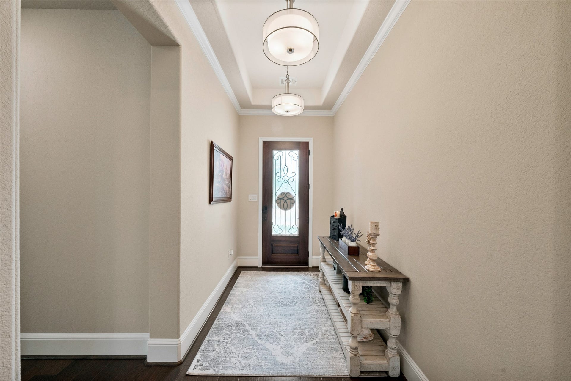 23926 Arcola Glen Lane, Katy, TX 77493 The entryway welcomes you with a sophisticated neutral color palette, featuring an elegant tray ceiling with crown molding and stunning dual hanging light fixtures.