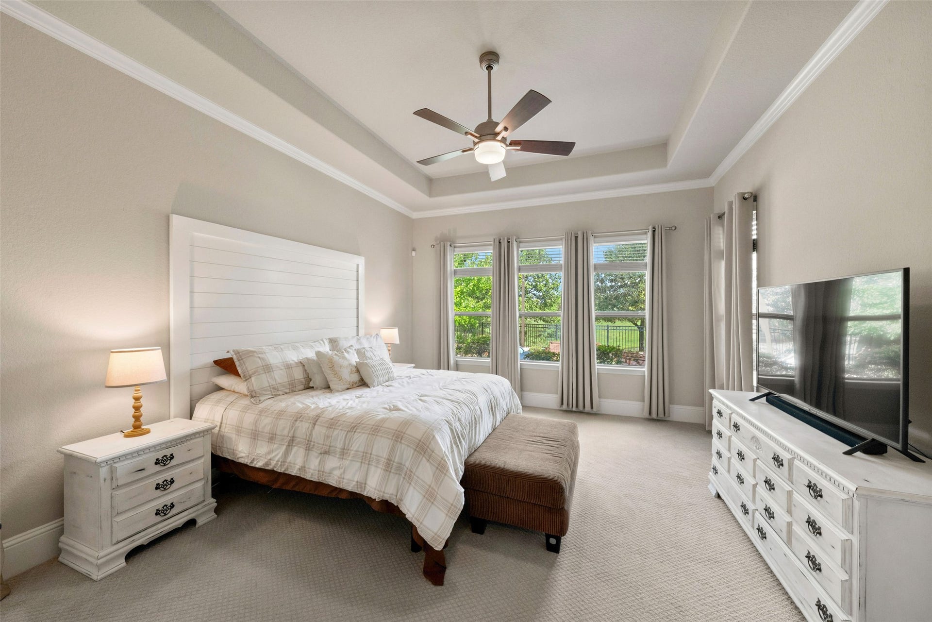 23926 Arcola Glen Lane, Katy, TX 77493 This primary suite offers a spacious layout with expansive windows and scenic views, highlighted by an elegant tray ceiling featuring custom crown molding.