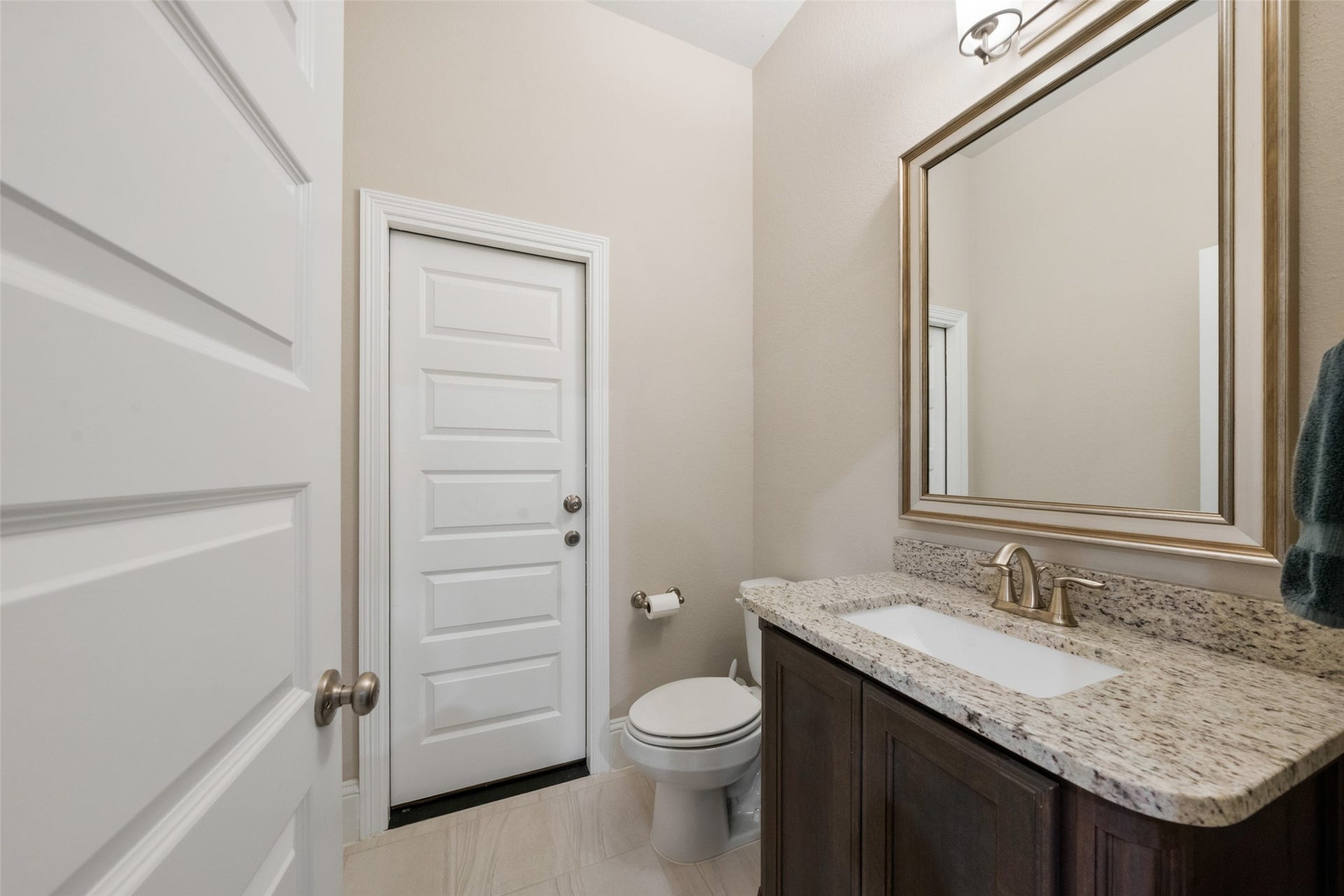 23926 Arcola Glen Lane, Katy, TX 77493 This elegant powder bath features a dark wood-stained vanity complemented by granite countertops and sophisticated champagne-finish fixtures.
