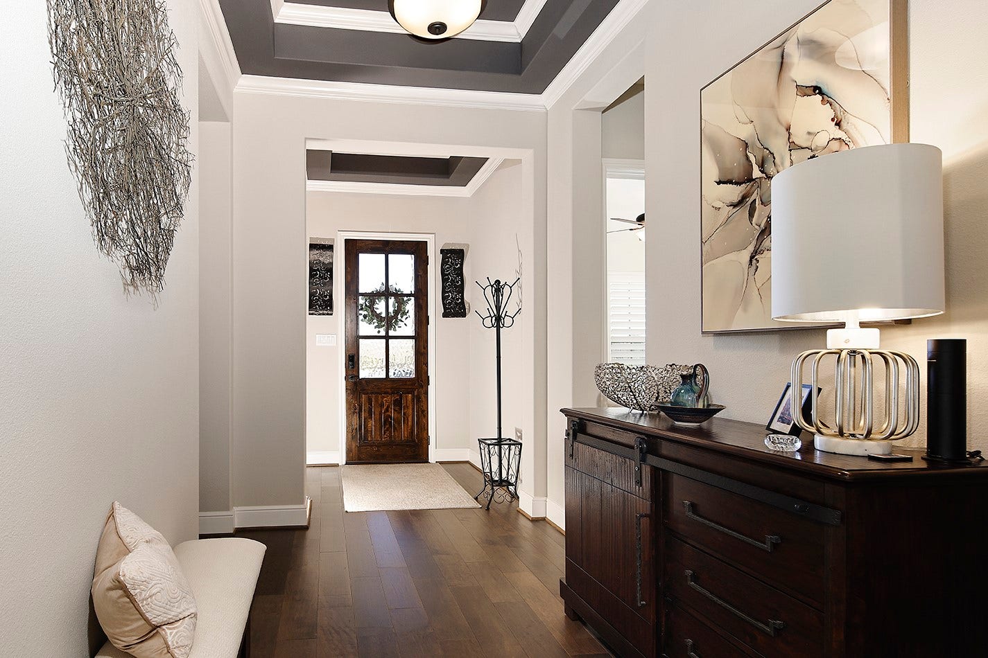 10135 Lehman Drive, Willis, TX 77318 This home features exquisite custom appointments throughout, highlighted by a rich, accent-colored tray ceiling that perfectly contrasts with the designer white walls and beautifully complements the warm wood flooring.