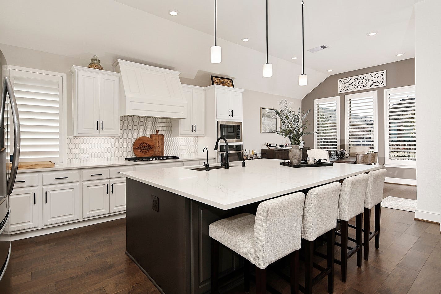 10135 Lehman Drive, Willis, TX 77318 Custom white cabinetry features modern black pulls that coordinate perfectly with the black kitchen faucet and pendant lighting. The honeycomb-patterned white tile backsplash adds unique character and visual interest to the space.