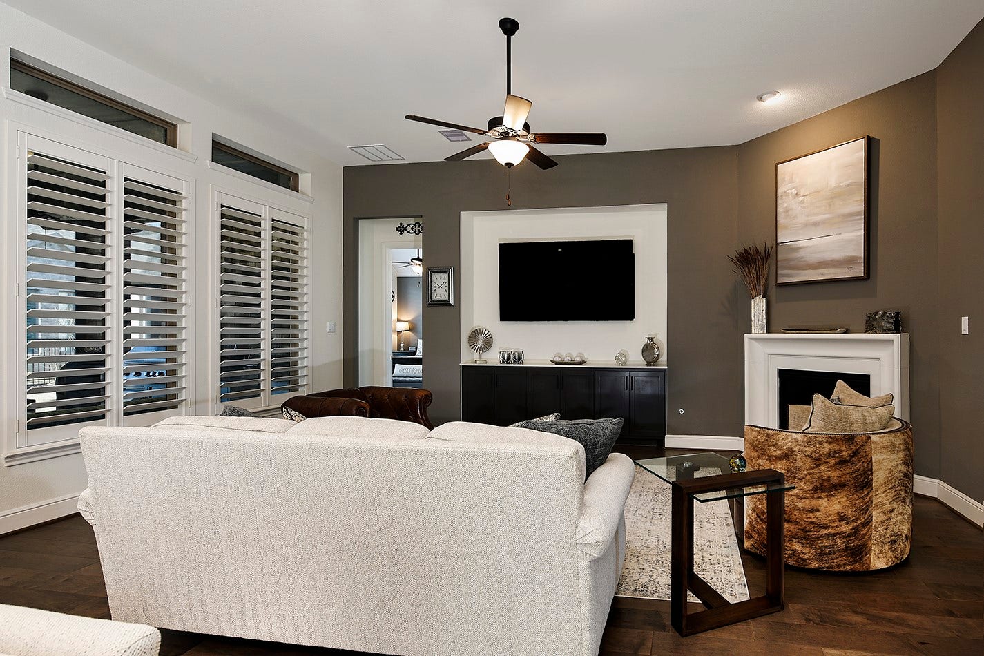 10135 Lehman Drive, Willis, TX 77318 This family room features a sophisticated, high-end aesthetic with dramatic, rich wall tones that beautifully contrast the modern white fireplace mantle. The built-in recessed niche for the television and cabinetry offers a seamless, space-saving design.