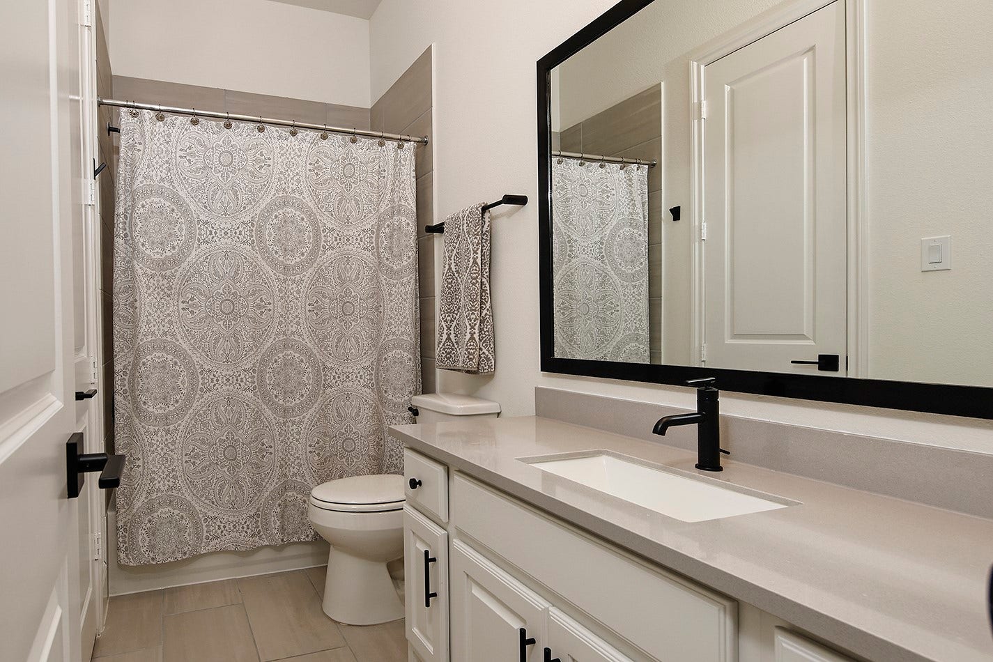 10135 Lehman Drive, Willis, TX 77318 The full bathroom features premium quartz countertops complemented by a modern rectangular sink, matte black fixtures, matching cabinet hardware, and a contemporary framed mirror.