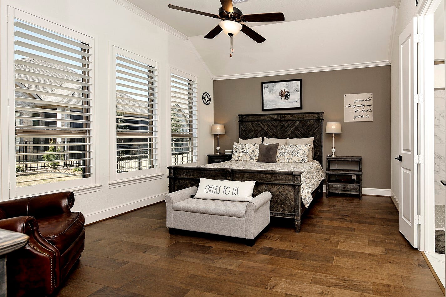 10135 Lehman Drive, Willis, TX 77318 Spacious primary suite featuring a wall of windows adorned with plantation shutters, elegant crown molding, and rich hardwood flooring for an upscale aesthetic.