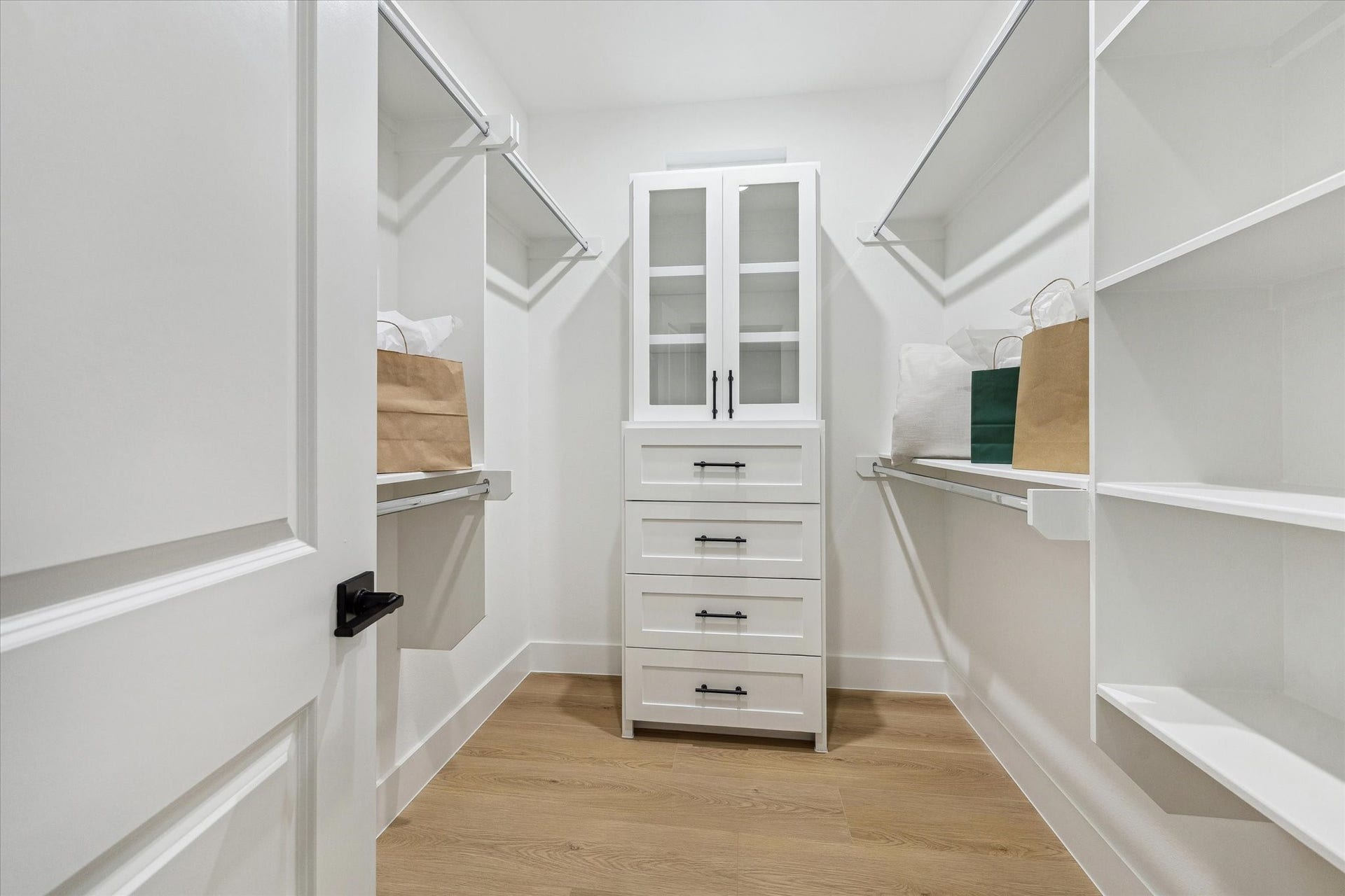Spacious walk-in closet featuring built-in shelving, ample hanging space, and a central cabinet with drawers for organized storage.