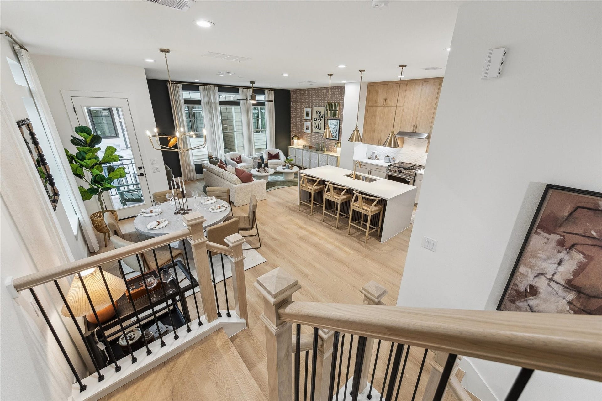 Open-concept living space with modern kitchen featuring a large island, stylish pendant lighting, and sleek cabinetry, seamlessly flowing into a cozy dining and living area with abundant natural light.
