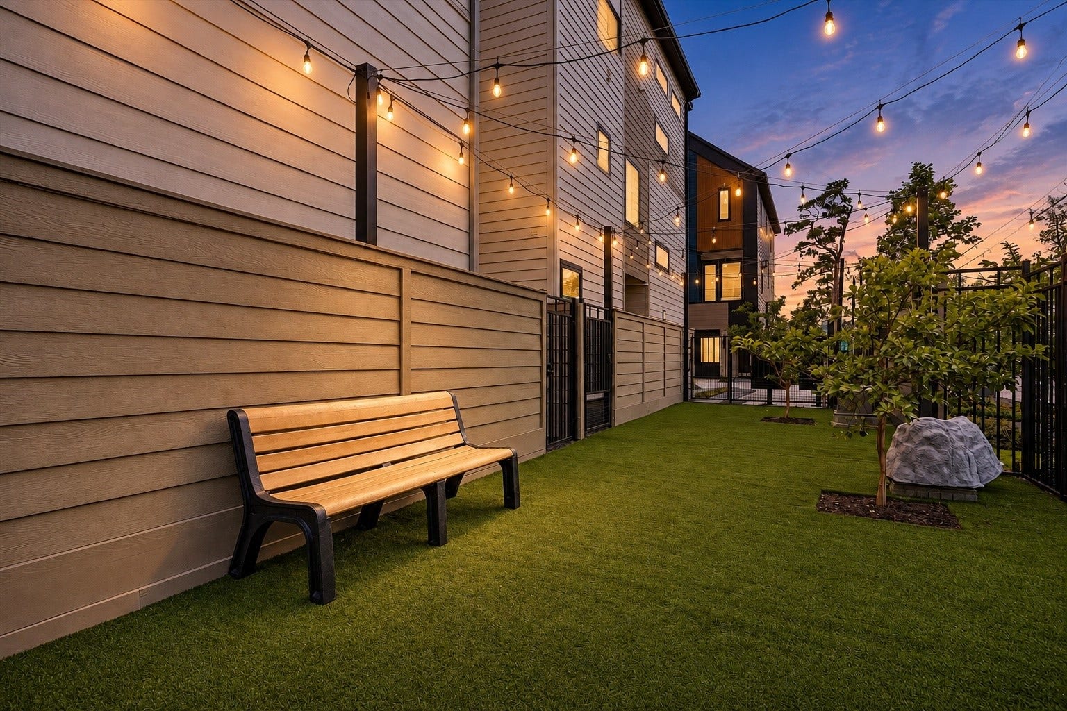 Charming backyard retreat with lush artificial grass, ambient string lights, and a cozy bench, perfect for evening relaxation.