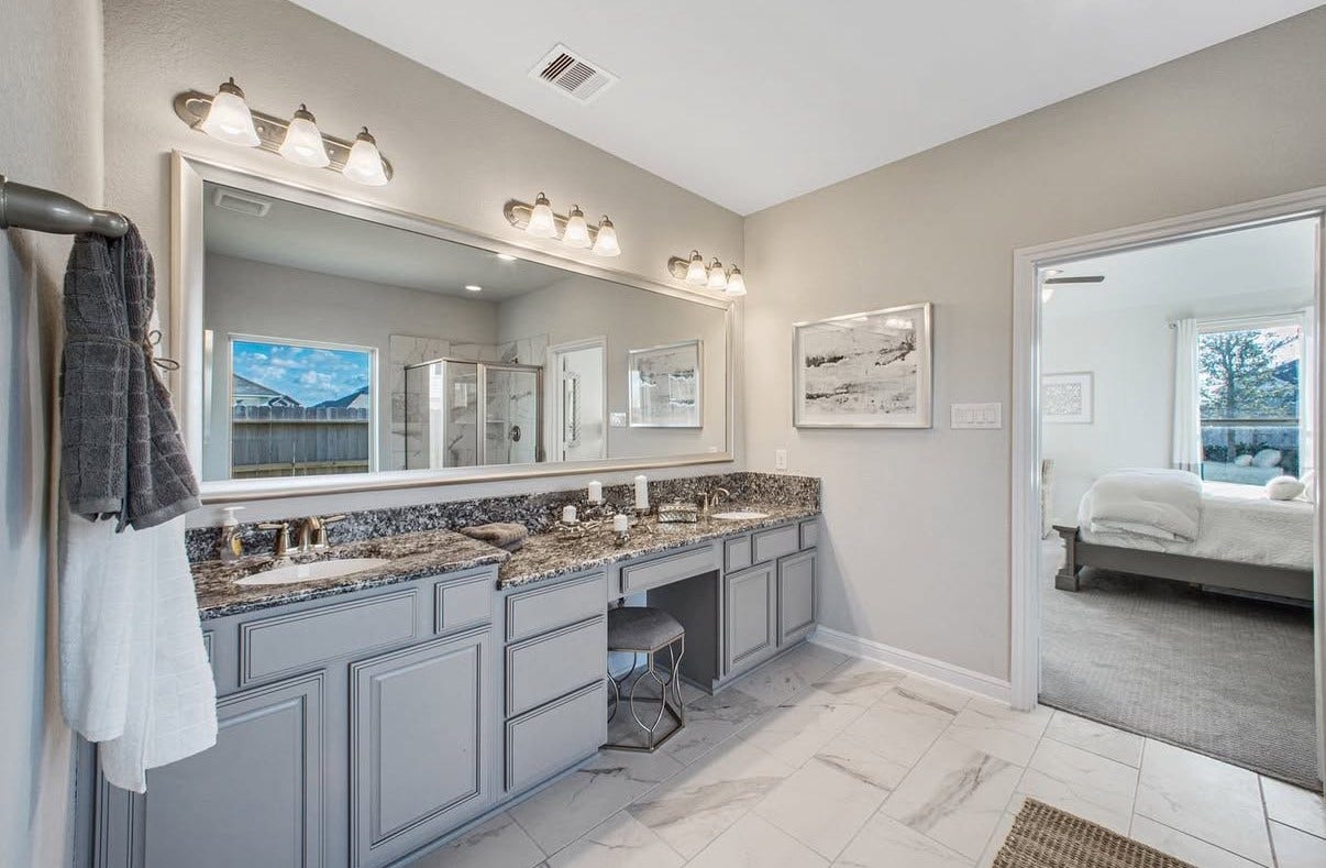 13201 Anchor Bay Drive, La Marque, TX 77568 Elegant primary bathroom featuring dual-sinks, granite countertops, a vanity, modern lighting, and a spacious glass-enclosed shower, seamlessly connected to a the cozy primary bedroom.