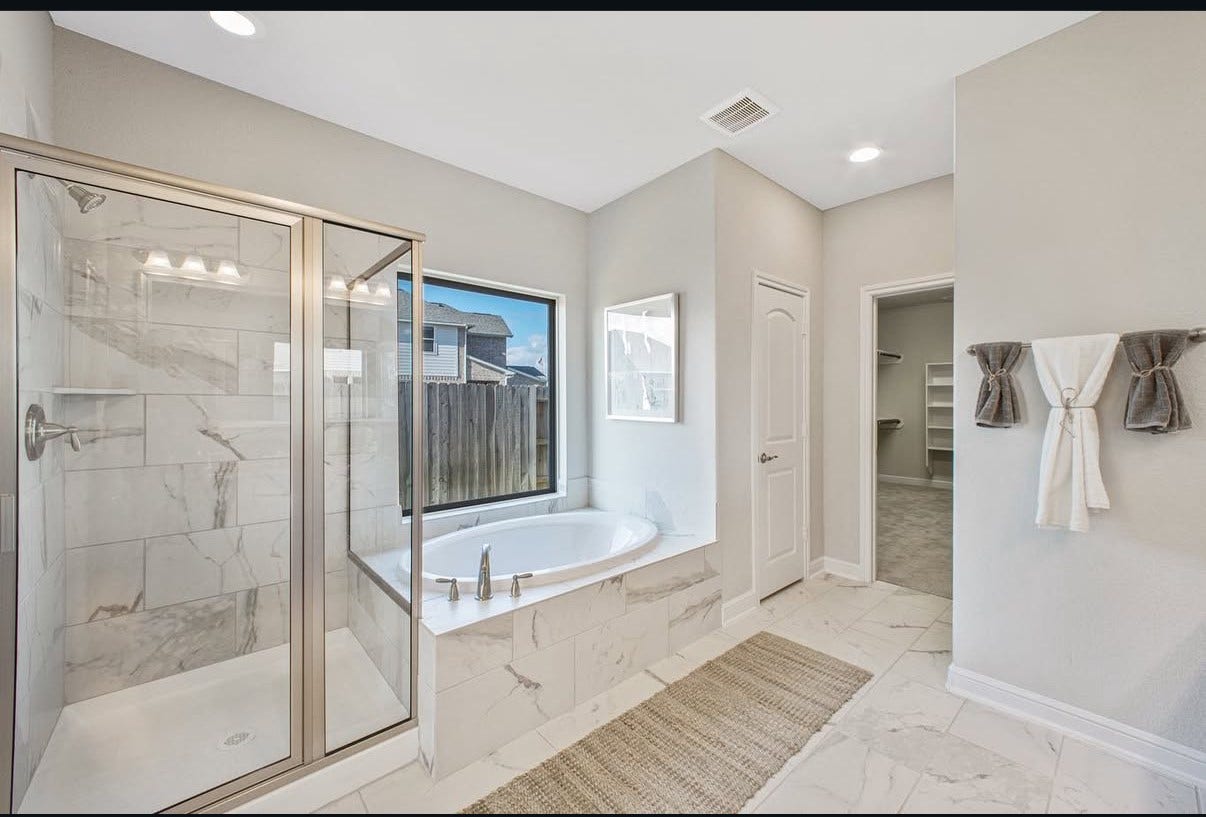13201 Anchor Bay Drive, La Marque, TX 77568 Elegant bathroom featuring a spacious glass-enclosed shower and a luxurious soaking tub with natural light pouring in through a large window.
