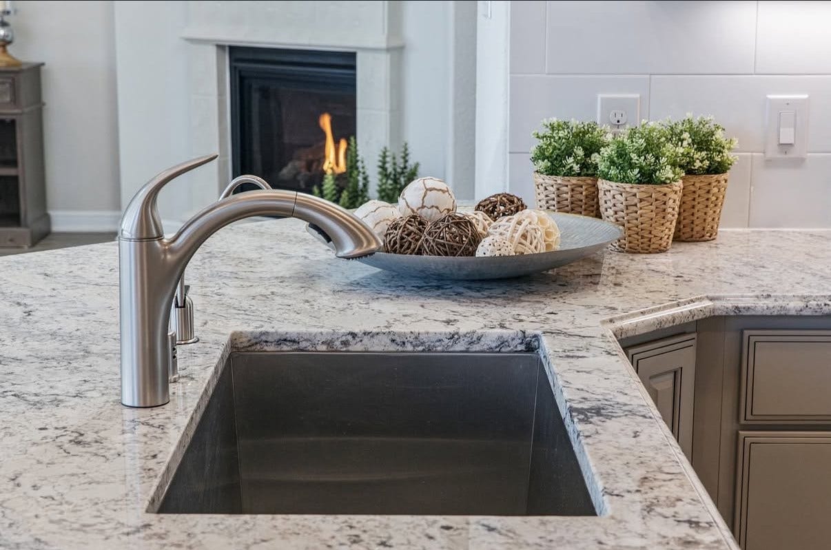13201 Anchor Bay Drive, La Marque, TX 77568 The kitchen space show cases a sleek stainless steel faucet and granite countertops, complemented by a cozy fireplace.