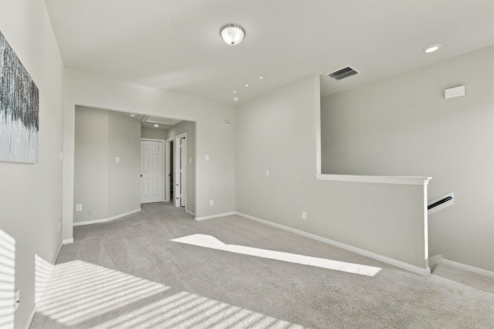 Bright upstairs family room with multiple windows and neutral carpeting.