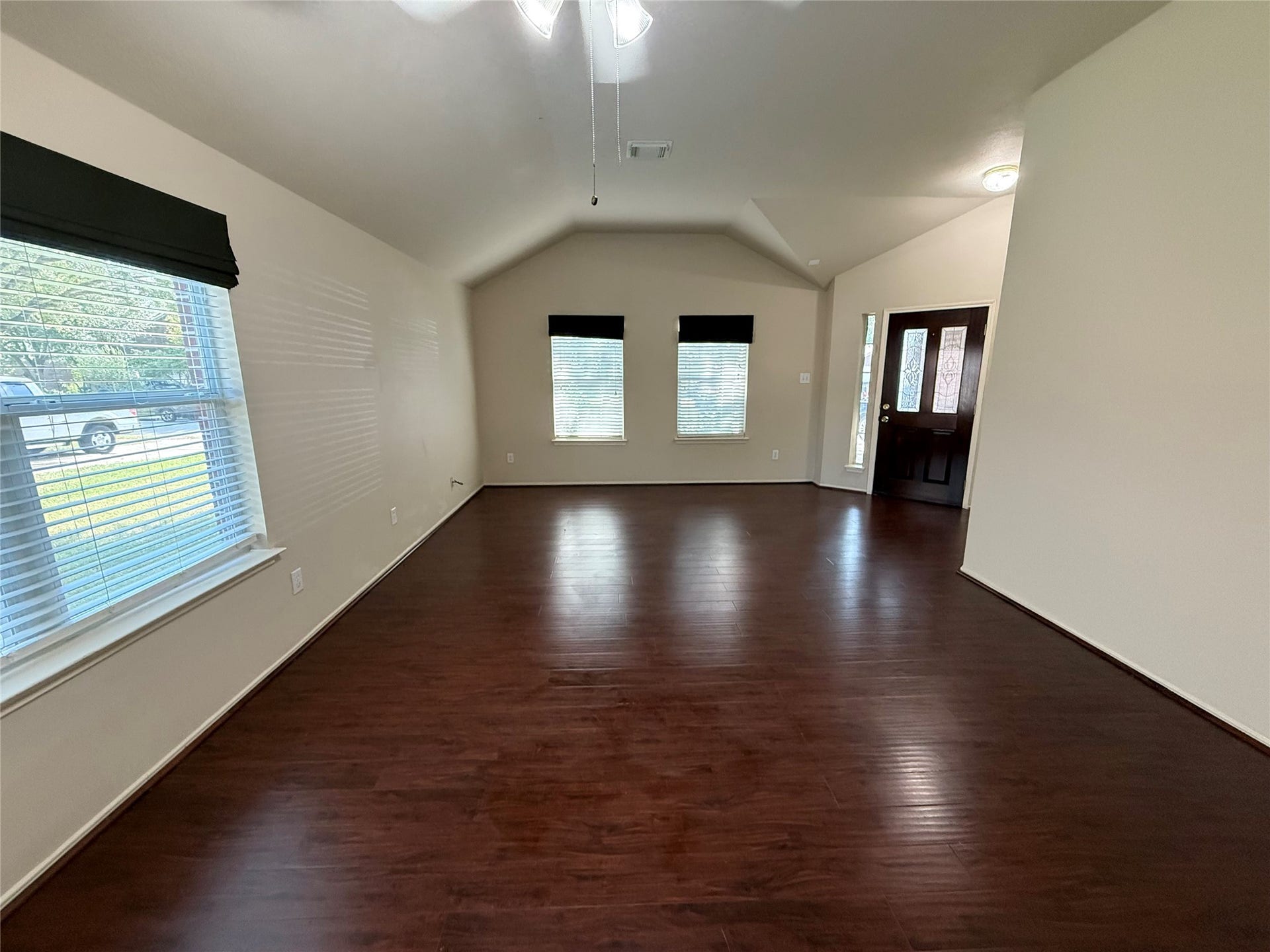 2104 Goldfinch Lane, League City, TX 77573 Step into this inviting, spacious living area with elegant dark wood flooring and abundant natural light, perfectly framing your front door as a welcoming centerpiece.