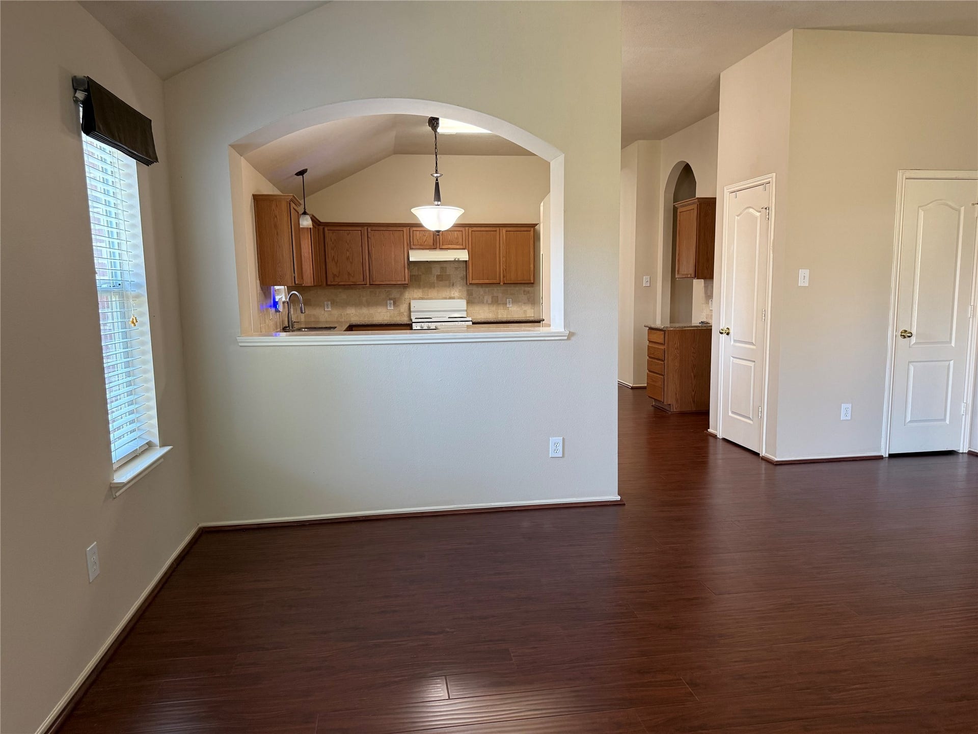 2104 Goldfinch Lane, League City, TX 77573 Bright and inviting open-concept living area with rich wood flooring, featuring a cozy kitchen with warm wooden cabinetry and a convenient pass-through opening.