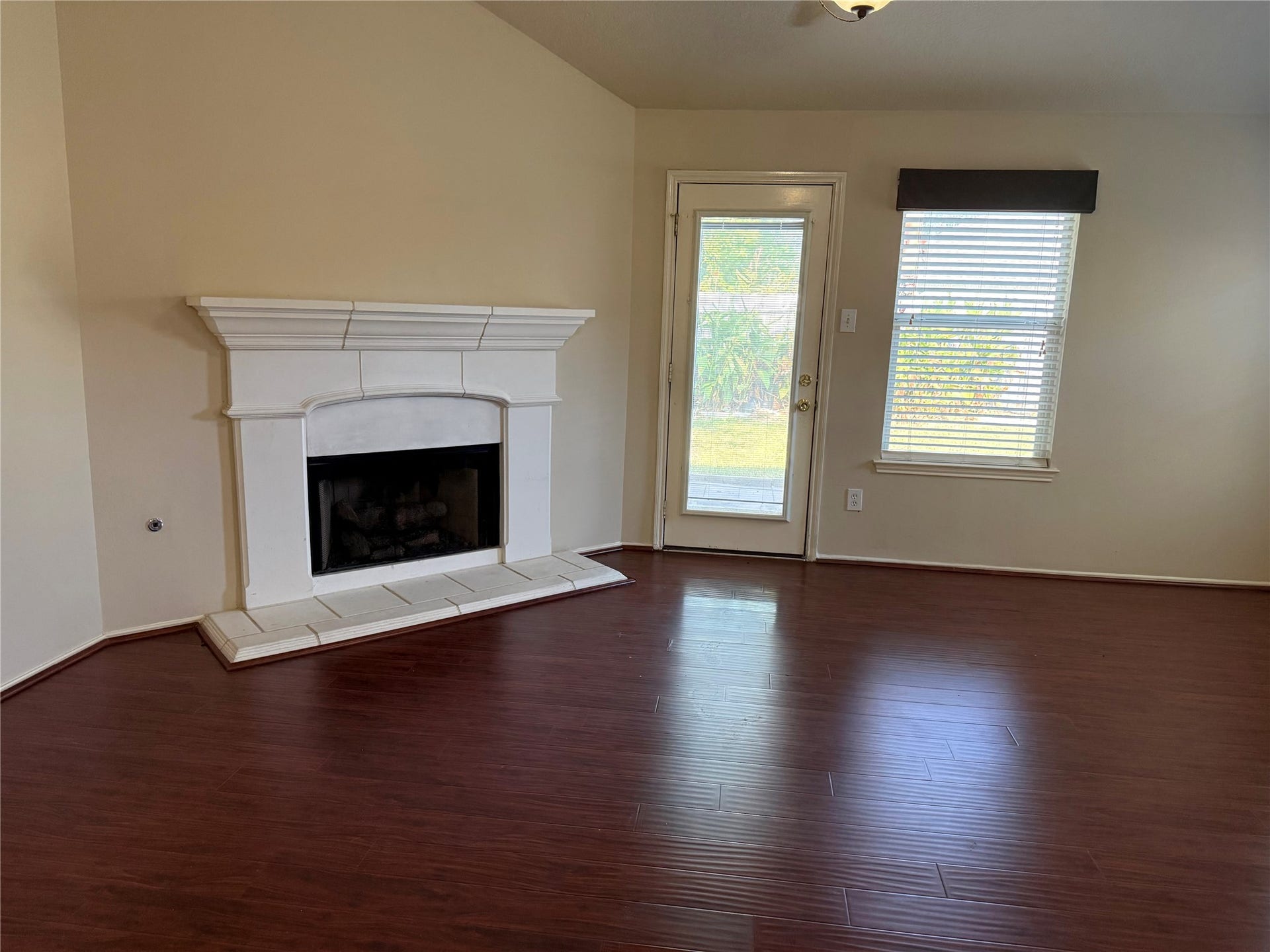 2104 Goldfinch Lane, League City, TX 77573 Inviting living area featuring a cozy fireplace, rich wood flooring, and abundant natural light from a large window and glass door leading outside.