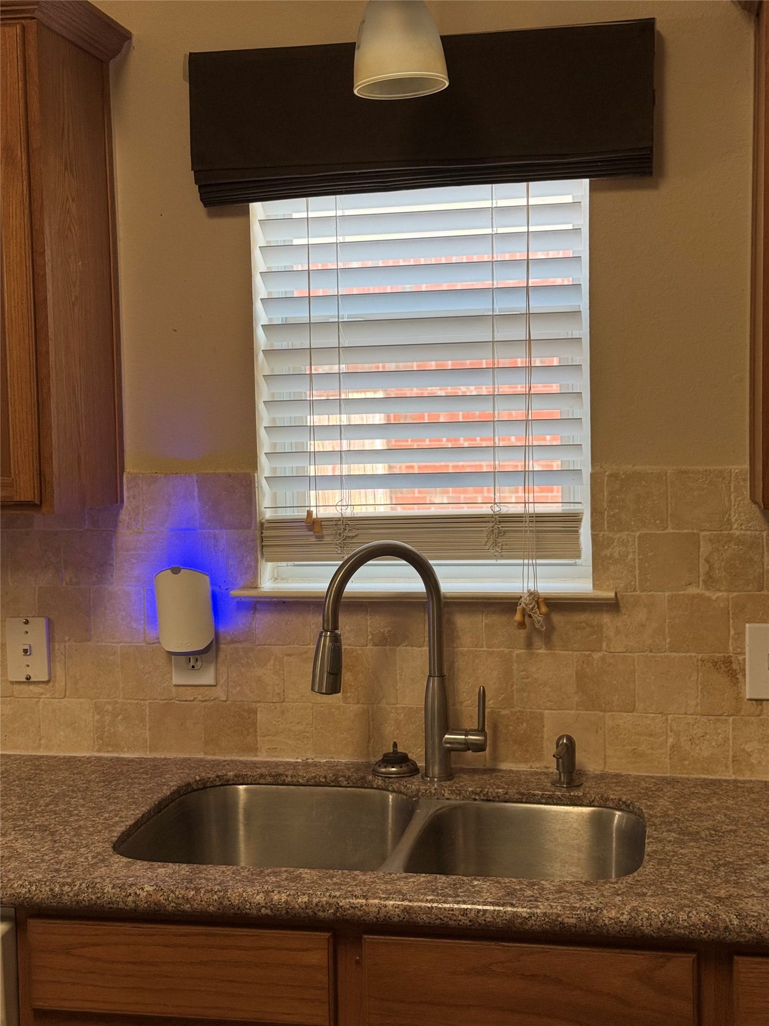 2104 Goldfinch Lane, League City, TX 77573 Cozy kitchen corner features a stainless steel double sink under a window with elegant blinds, complemented by warm wooden cabinetry and a stylish backsplash.