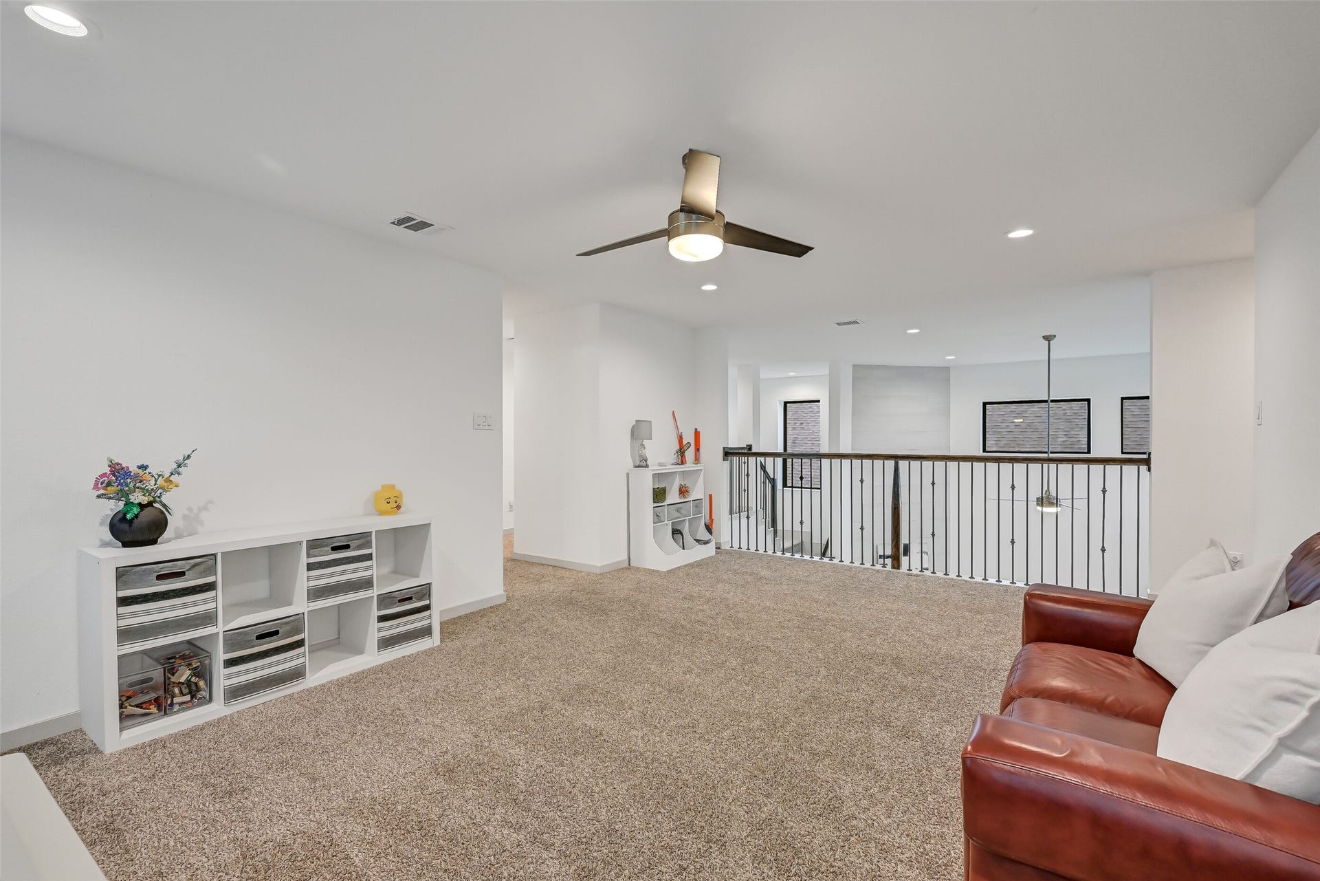 1570 Mustang Trail, Friendswood, TX 77546 The spacious upstairs game room offers plenty of room for lounging, play, hobbies, or gaming while remaining open to the family room below. Plush carpet, recessed lighting, a ceiling fan, and iron railing define this versatile second-floor gathering space.