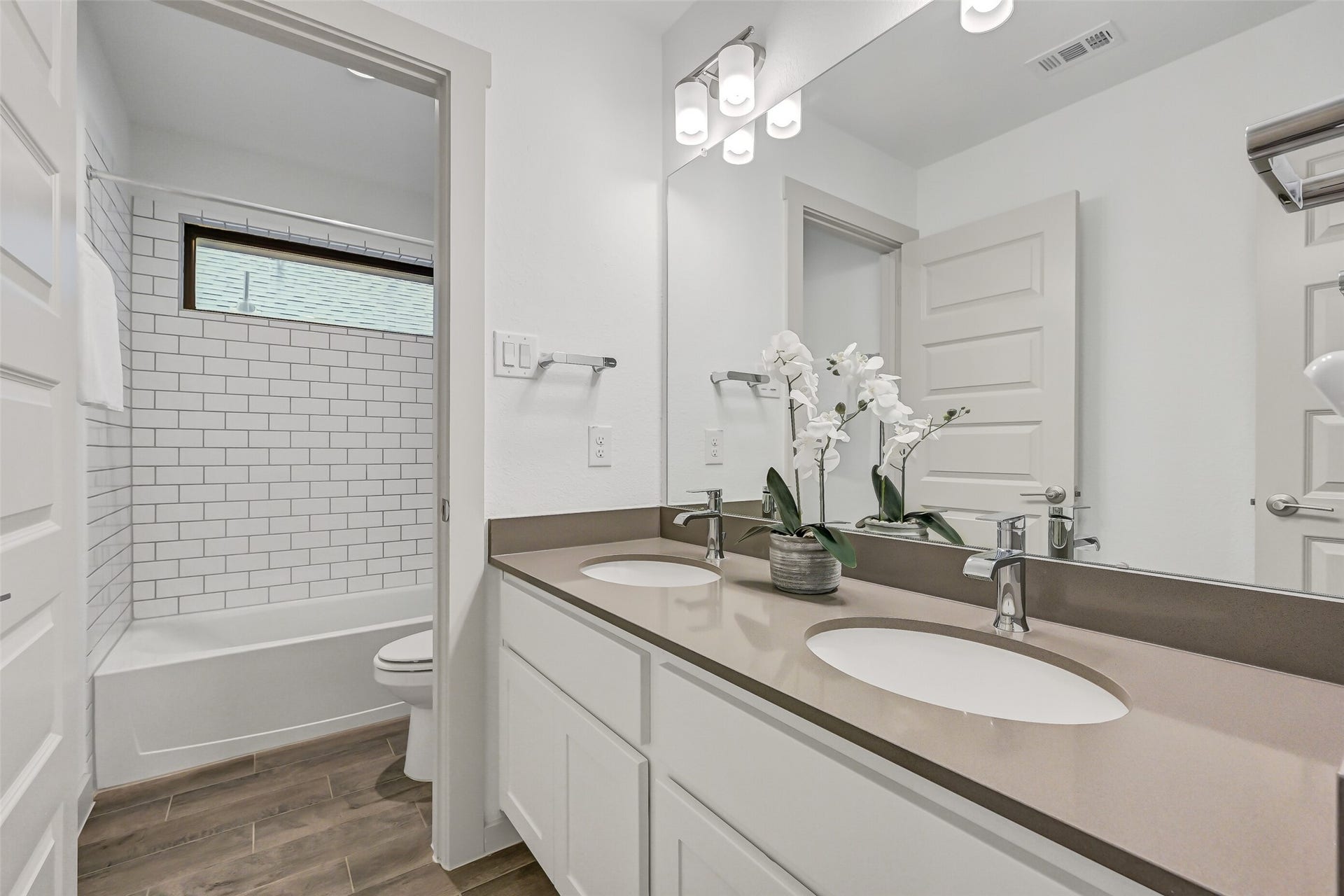 1570 Mustang Trail, Friendswood, TX 77546 Designed with busy households in mind, this upstairs secondary bath features dual sinks, generous counter space, white shaker cabinetry, modern fixtures, and a separate tub/shower area finished with crisp white subway tile.