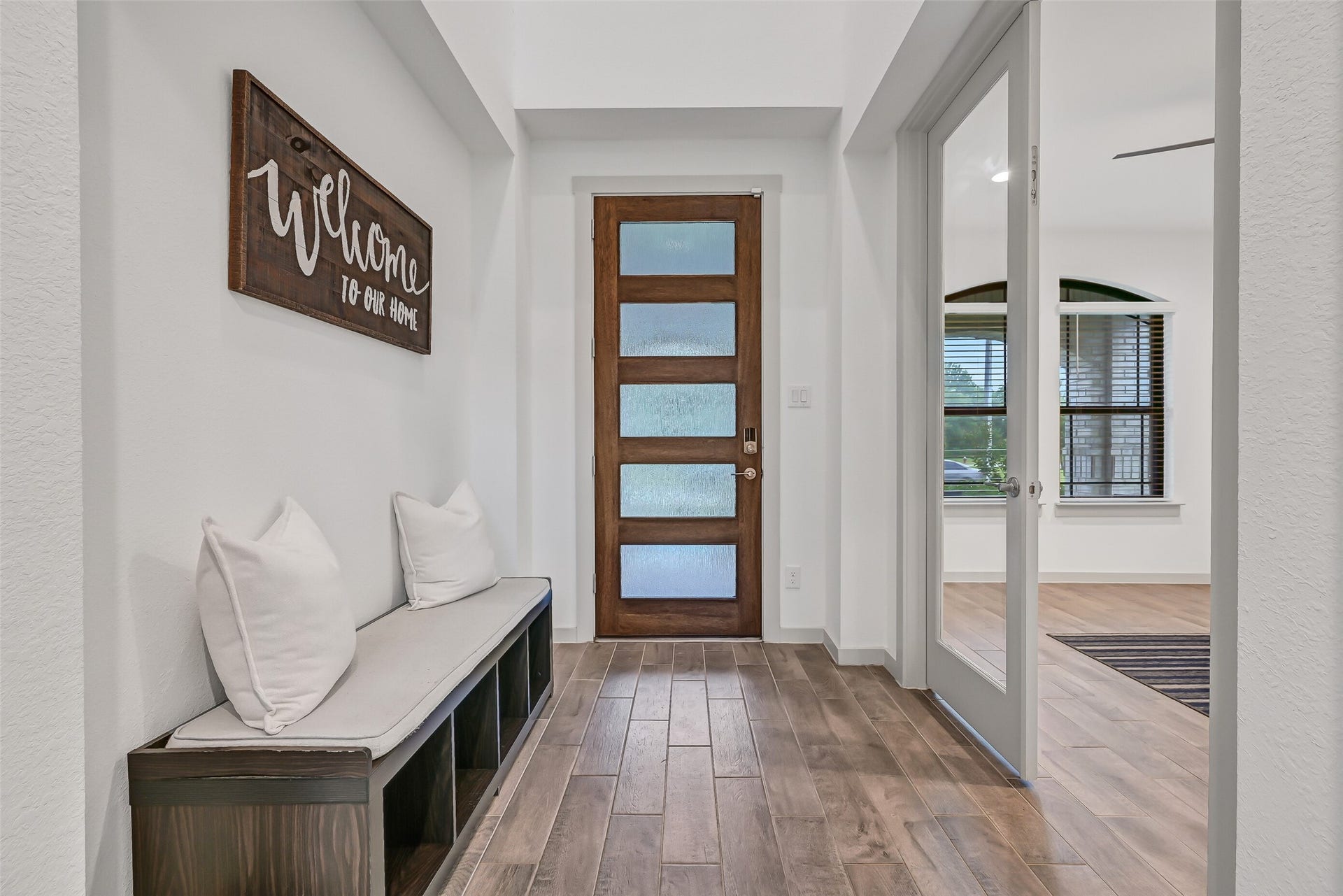 1570 Mustang Trail, Friendswood, TX 77546 The welcoming foyer pairs clean modern finishes with a handsome wood-and-glass front door, durable wood-look tile flooring, and convenient bench seating, while glass French doors provide privacy for the dedicated first-floor home office.