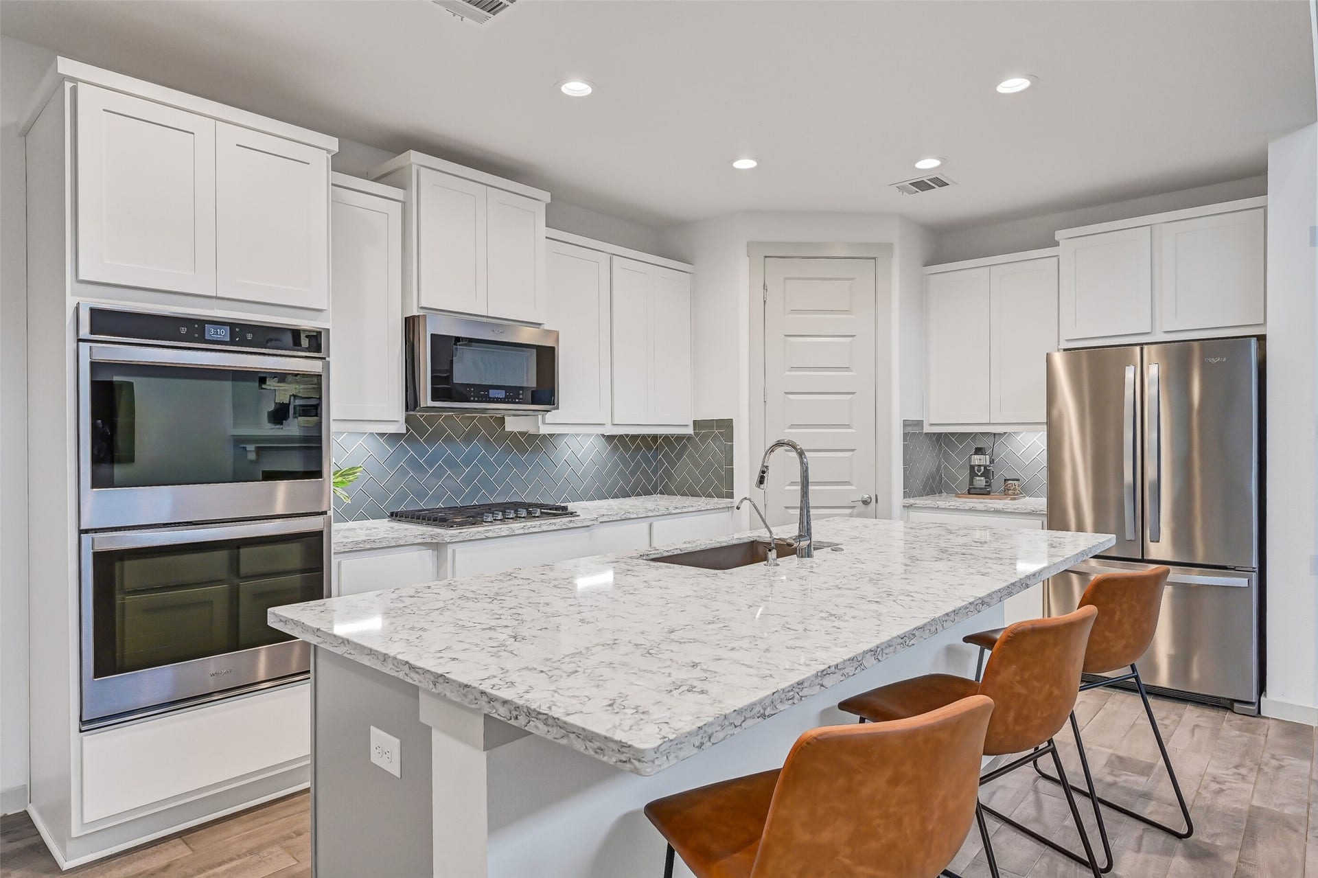 1570 Mustang Trail, Friendswood, TX 77546 Thoughtfully designed for serious cooking, the kitchen features quartz counters, a gas cooktop, double ovens, built-in microwave, abundant cabinetry, and a designer herringbone backsplash, with the oversized island providing even more workspace.