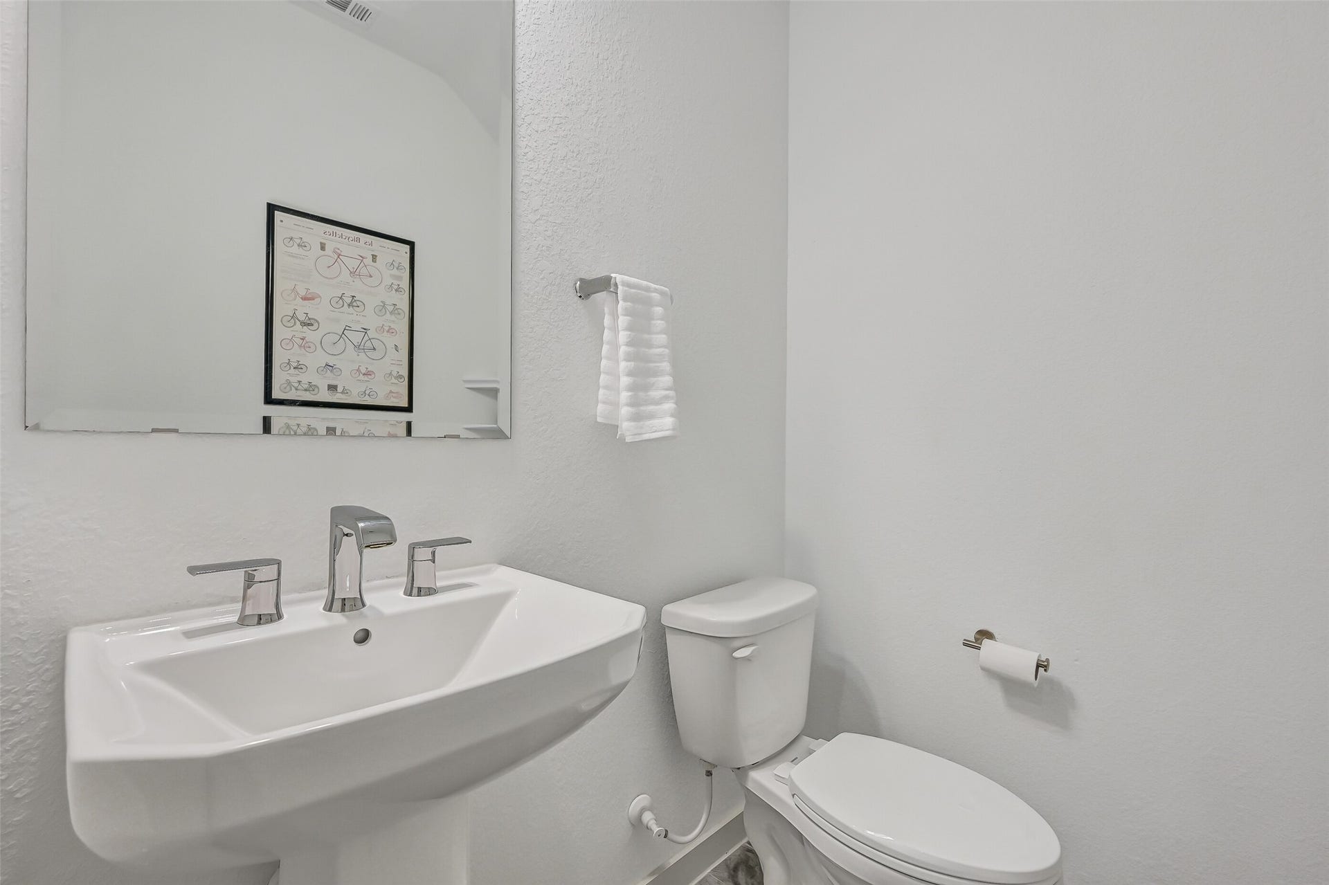 1570 Mustang Trail, Friendswood, TX 77546 A convenient first-floor powder bath serves guests with a clean, contemporary design featuring a pedestal sink, modern chrome fixtures, oversized mirror, and neutral finishes that coordinate beautifully with the rest of the home.
