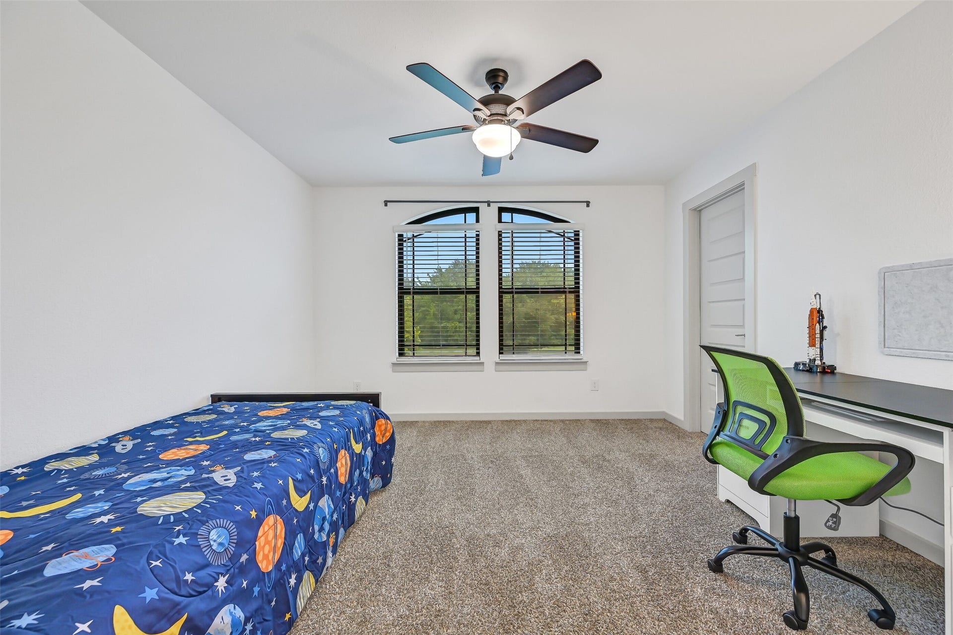 1570 Mustang Trail, Friendswood, TX 77546 Bright and spacious, this secondary bedroom features plush carpet, a ceiling fan, a charming arched window detail, and plenty of room for both sleeping and study areas. A neutral palette makes it easy for the next owner to personalize.