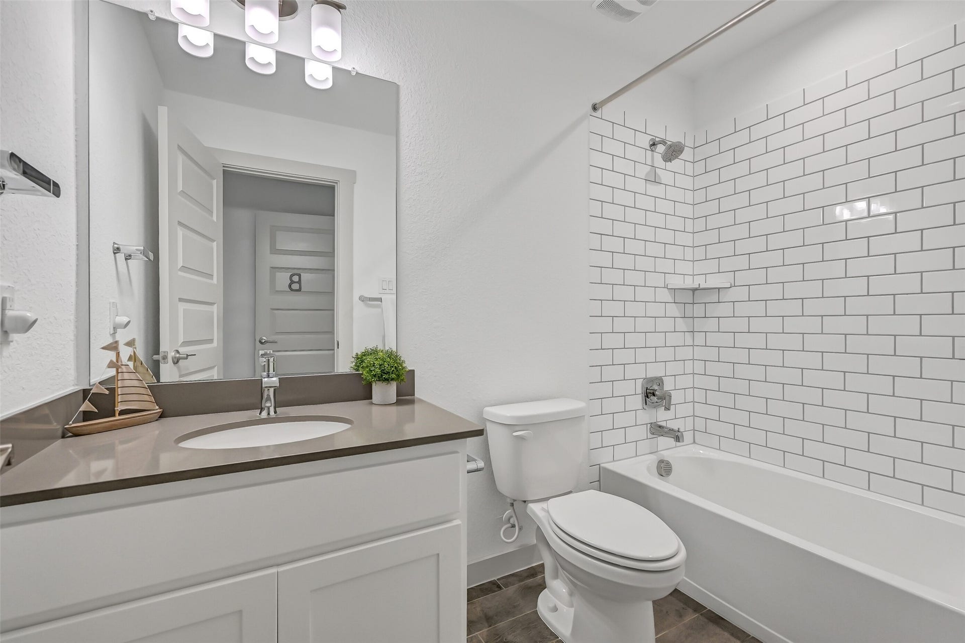 1570 Mustang Trail, Friendswood, TX 77546 A closer look at the secondary bath highlights the clean white subway-tile tub/shower surround, contemporary fixtures, neutral finishes, and practical layouta fresh, timeless space conveniently positioned near the upstairs bedrooms.