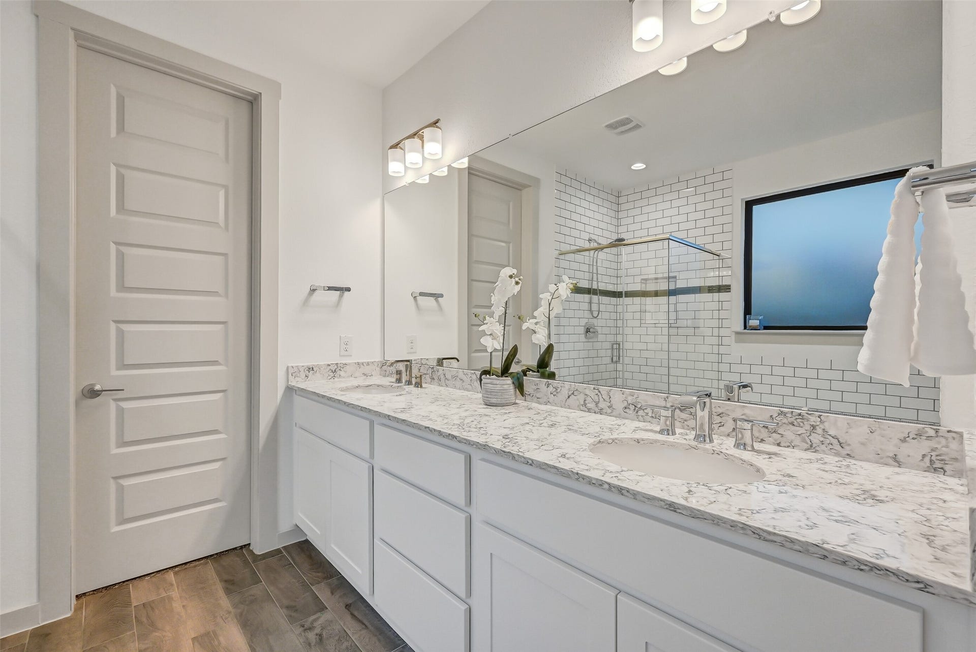1570 Mustang Trail, Friendswood, TX 77546 The spacious primary bath features an extended quartz-topped vanity with dual sinks, abundant drawer and cabinet storage, a wall-spanning mirror, modern fixtures, and easy access to both the large walk-in closet and beautifully tiled bathing area.