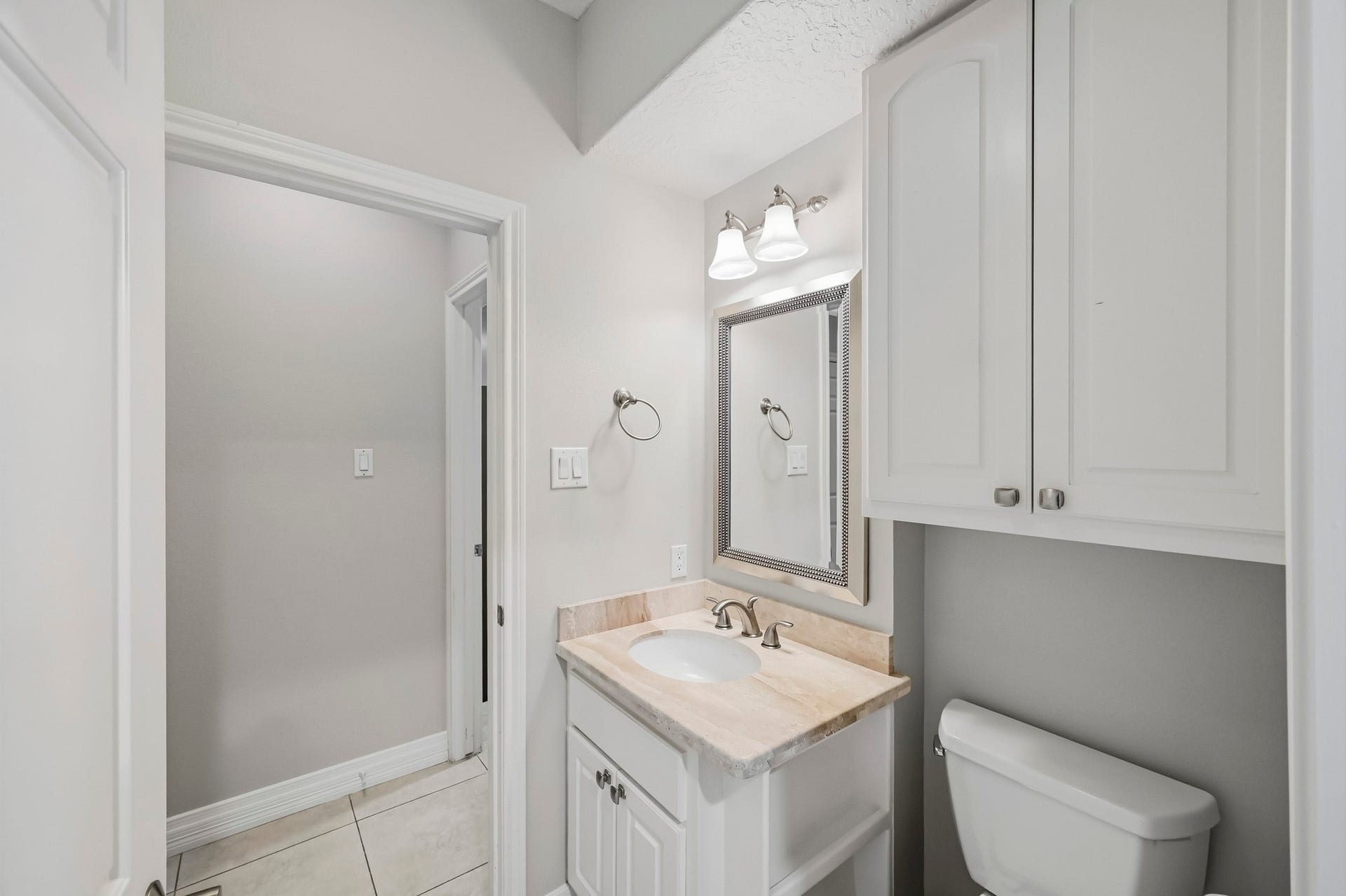 9354 Escondido Drive, Willis, TX 77318 A convenient full bathroom adjoining the study features a stone-topped vanity, framed mirror, decorative lighting and built-in storage.