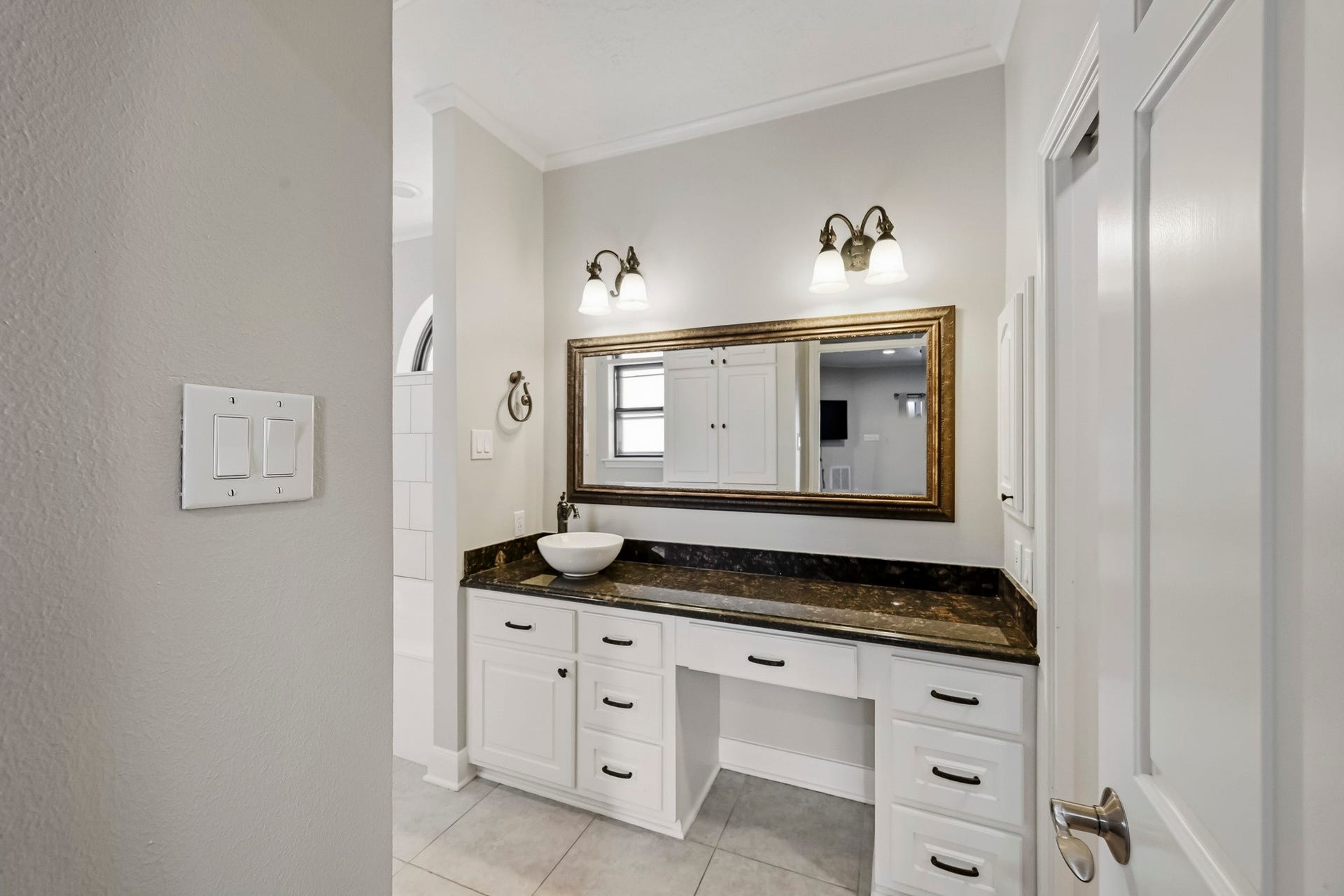 9354 Escondido Drive, Willis, TX 77318 One of TWO primary bathrooms! This beautifully appointed space features an extended granite vanity, vessel sink, framed mirror, decorative lighting and abundant cabinet storage.