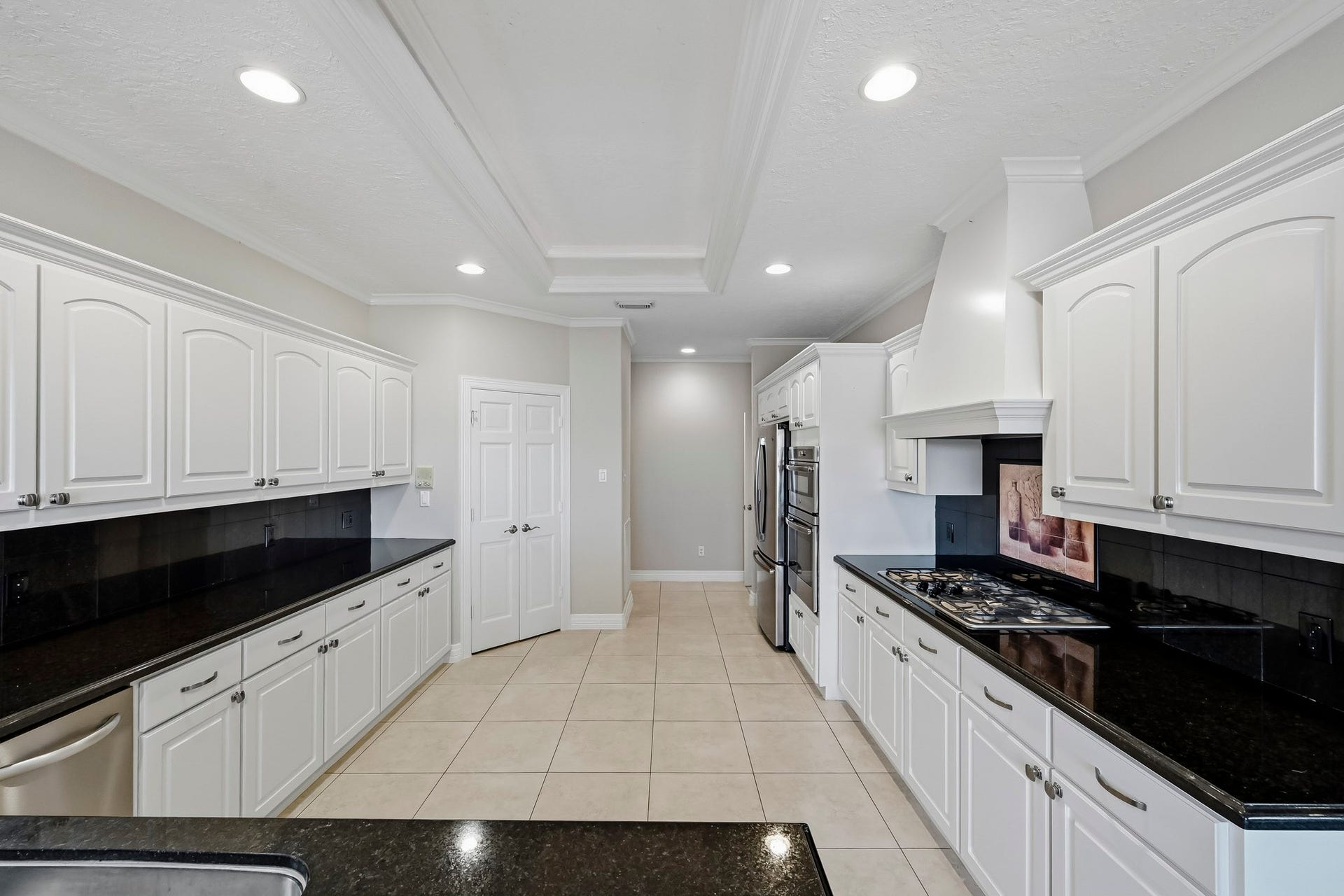 9354 Escondido Drive, Willis, TX 77318 A gas cooktop, custom vent hood and extensive cabinetry make this kitchen as practical as it is inviting!