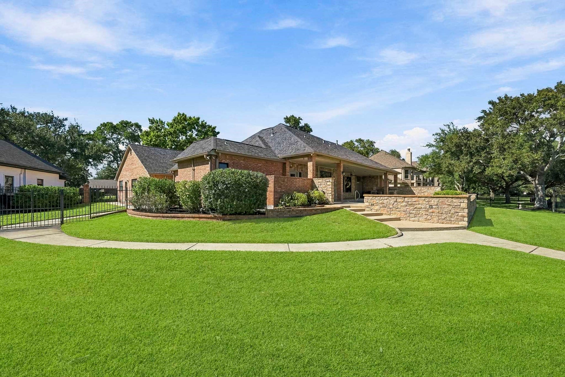 9354 Escondido Drive, Willis, TX 77318 Beautifully maintained grounds surround this custom waterfront home, with a curved walkway leading toward the pool and outdoor living areas.