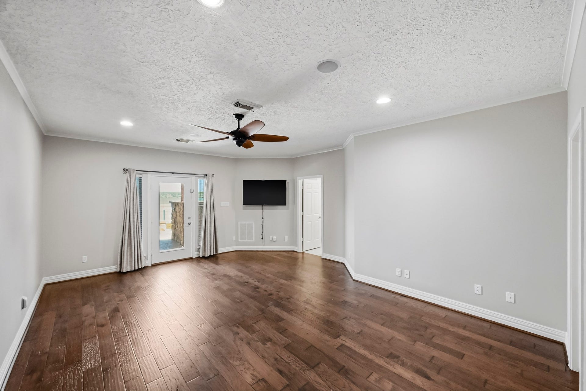 9354 Escondido Drive, Willis, TX 77318 Retreat to the spacious primary suite featuring wood-look tile flooring, recessed lighting and direct access to the covered patio.